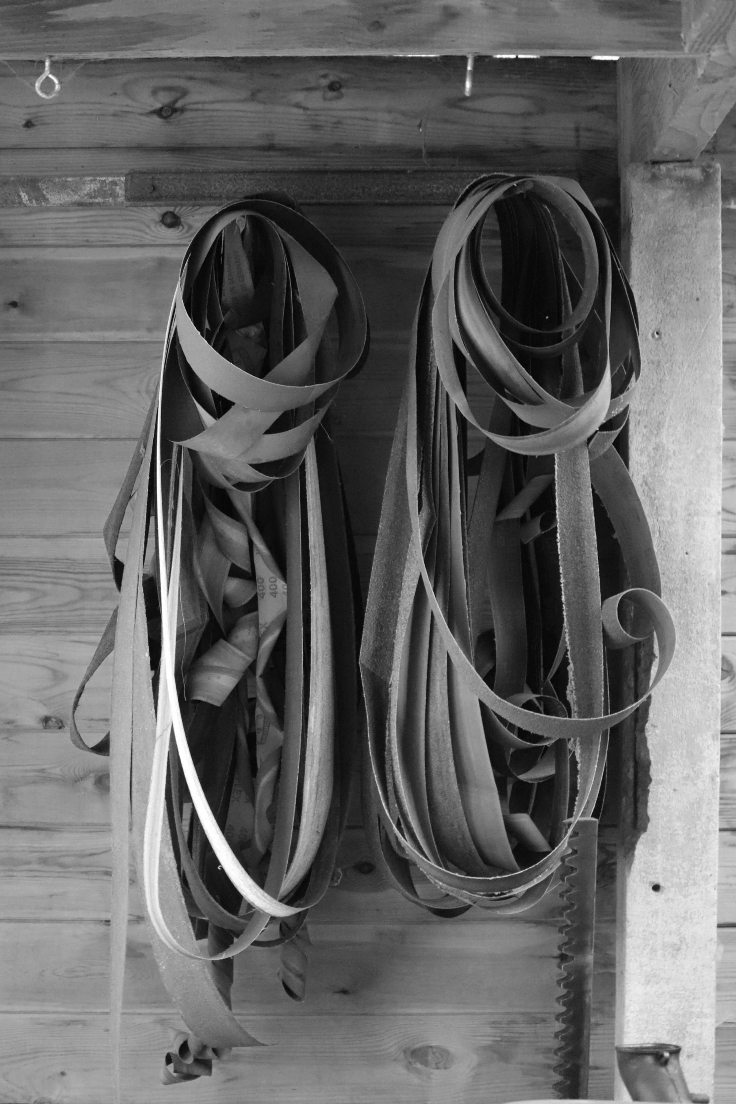 Two loops of rubber and stripping materials hanging on a hook against a wooden wall.