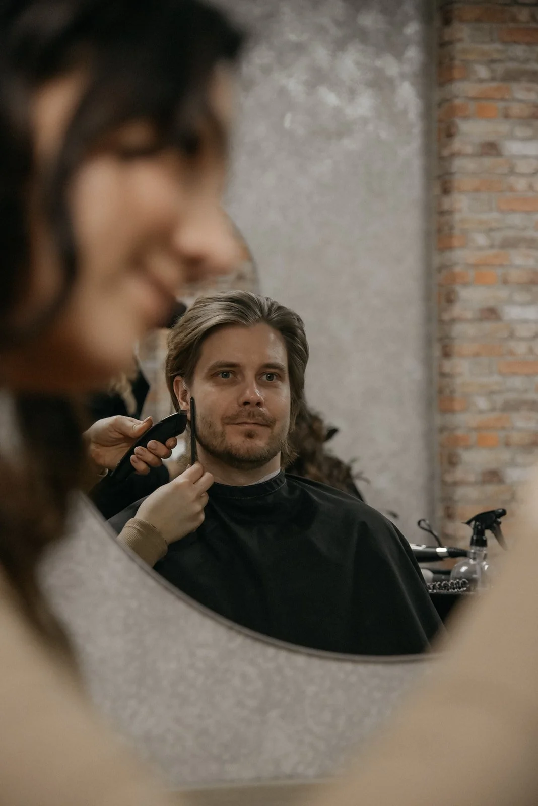 Hykken brändikuvaukset yrityksen omissa tiloissa. Kampaaja ajaa asiakkaan hiuksia.