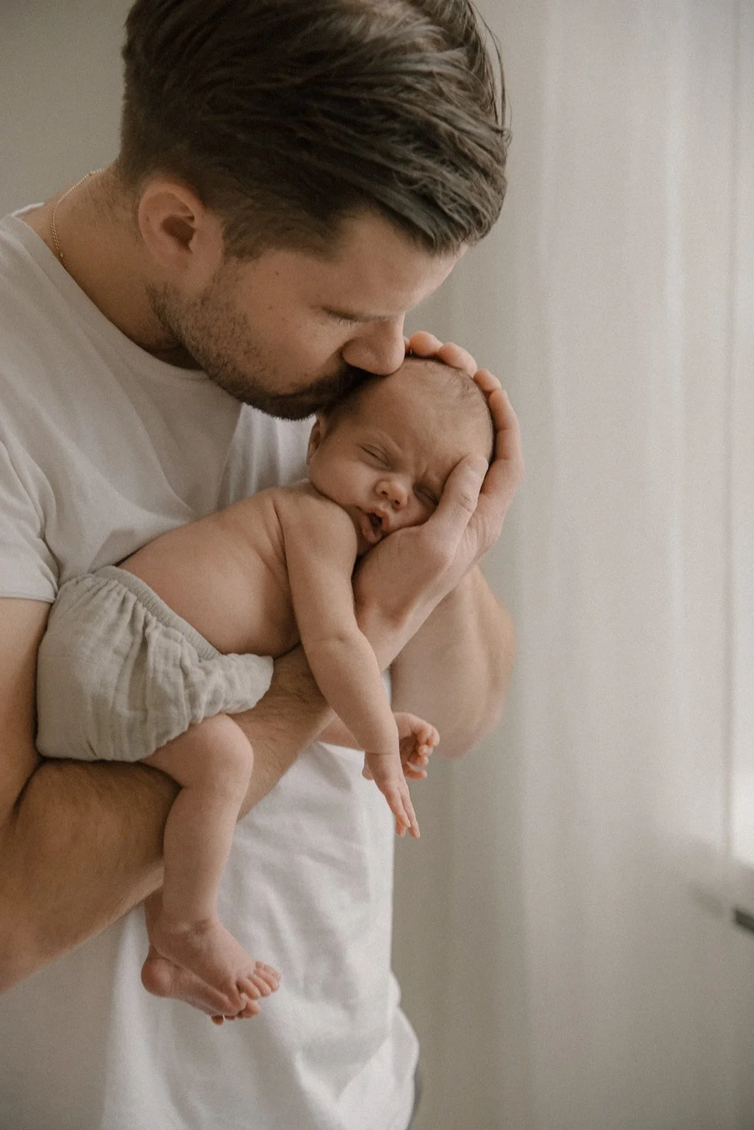 Vastasyntynyt vauva isän sylissä. Vauvakuvaus studiolla.