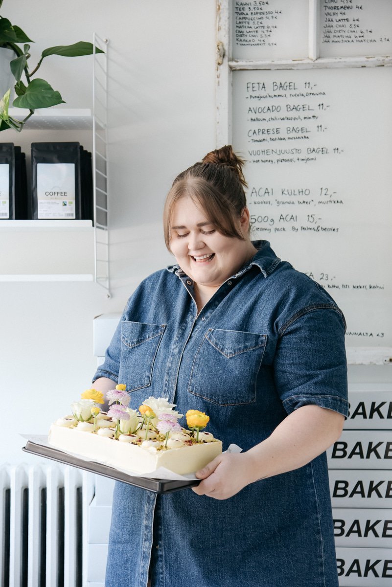 Bakerikan yrittäjä pitelee kakkua käsissään. Kuvannut yrityskuvaaja Heidi Väisänen.