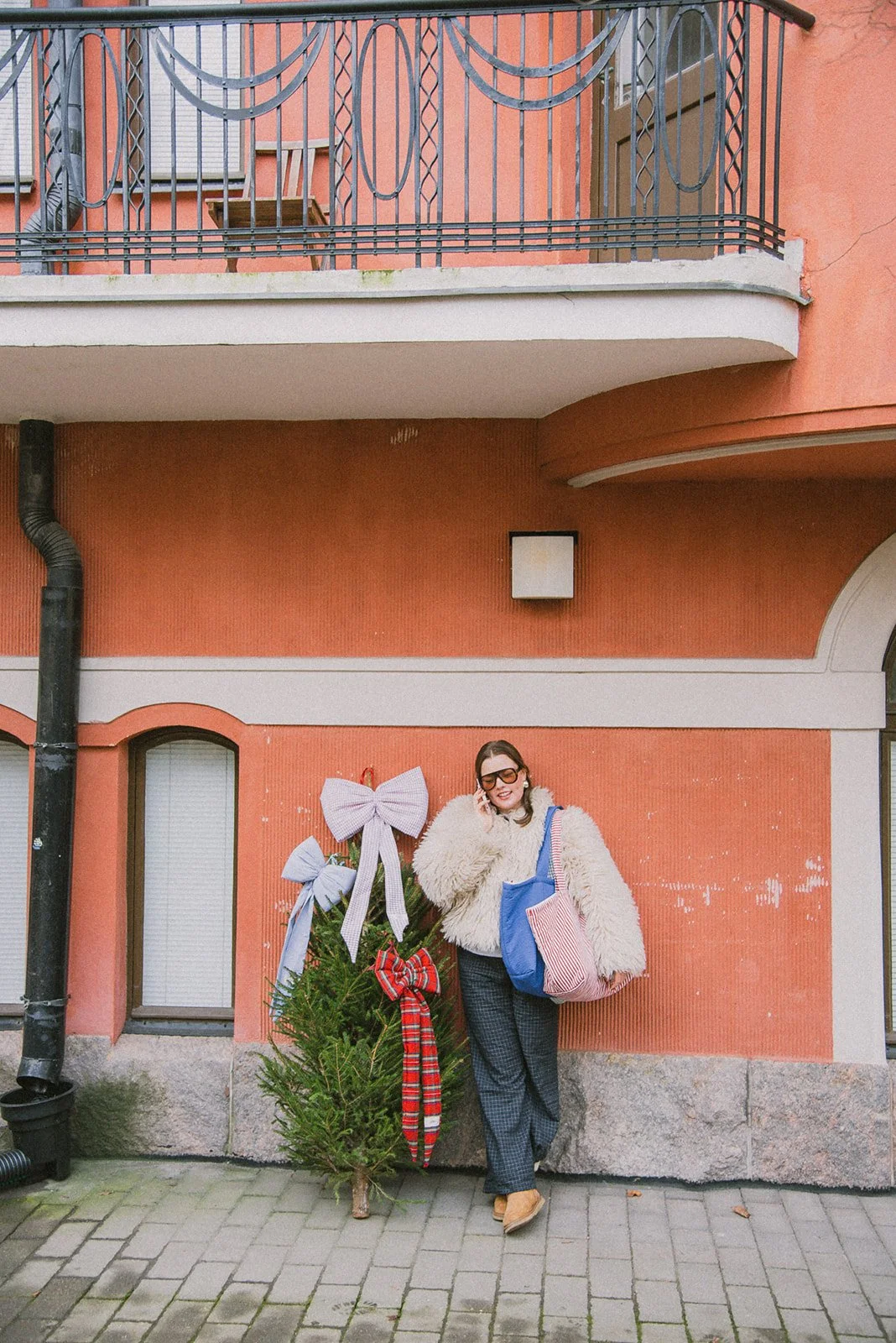 Edlan brändikuvaus, yrittäjällä brändin kasseja olalla, nojaa seinään kaupunkimaisemassa.