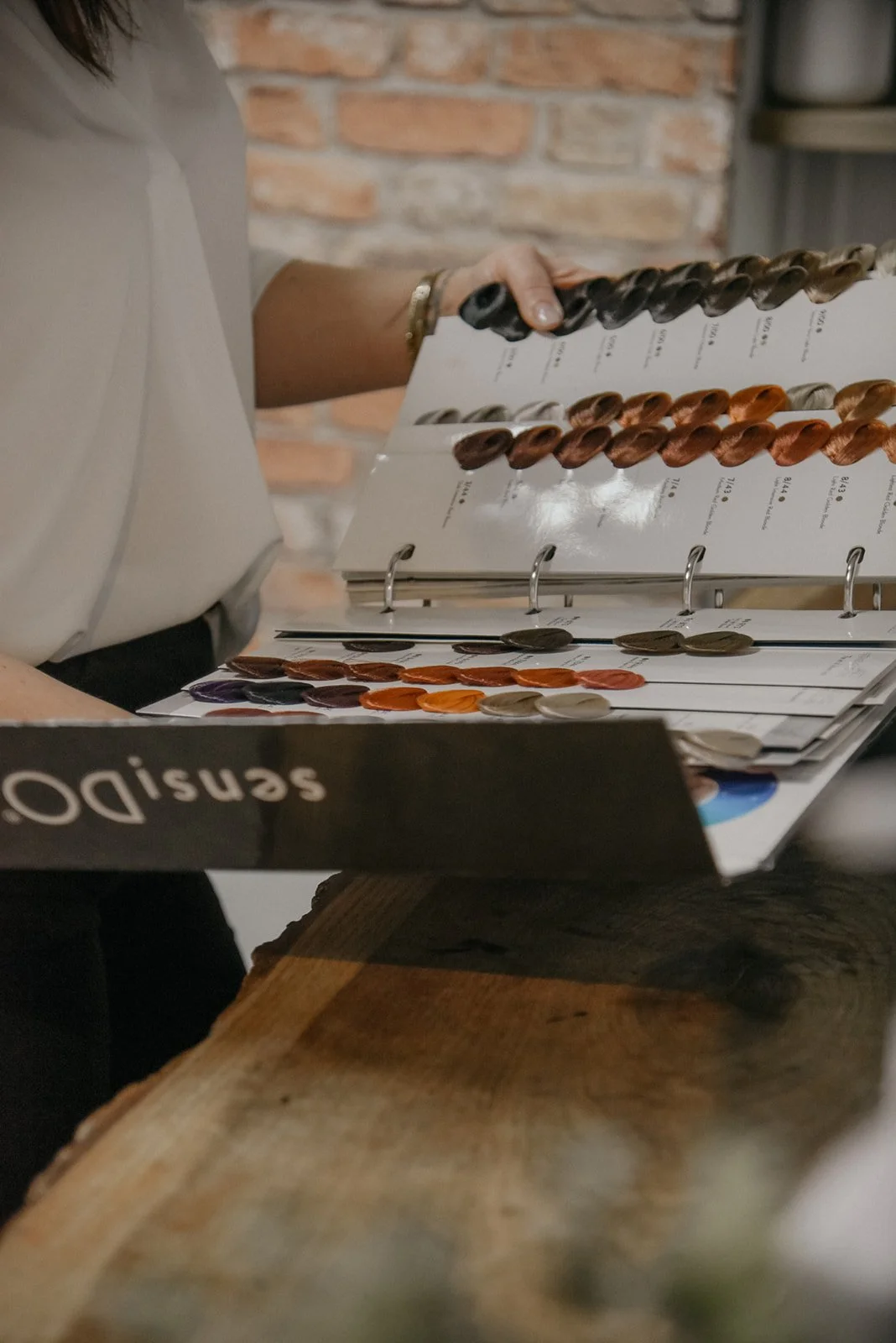 Yrityskuvaukset kampaamossa, kampaaja selaa värikarttaa.