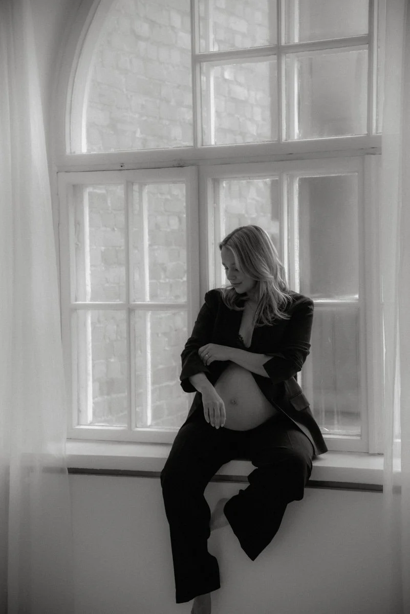 Odottava äiti istuu ikkunalaudalla ison ikkunan edessä Heidi Väisäsen valoisalla studiolla Keravalla.