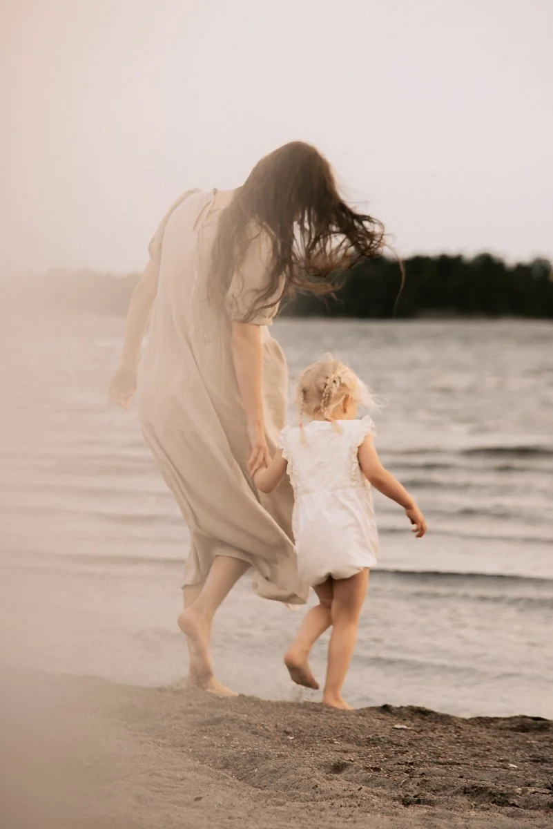 Perhekuvaus miljöössä, äiti ja pieni lapsi kävelevät kohti merta. Kuvannut valokuvaaja Heidi Väisänen.