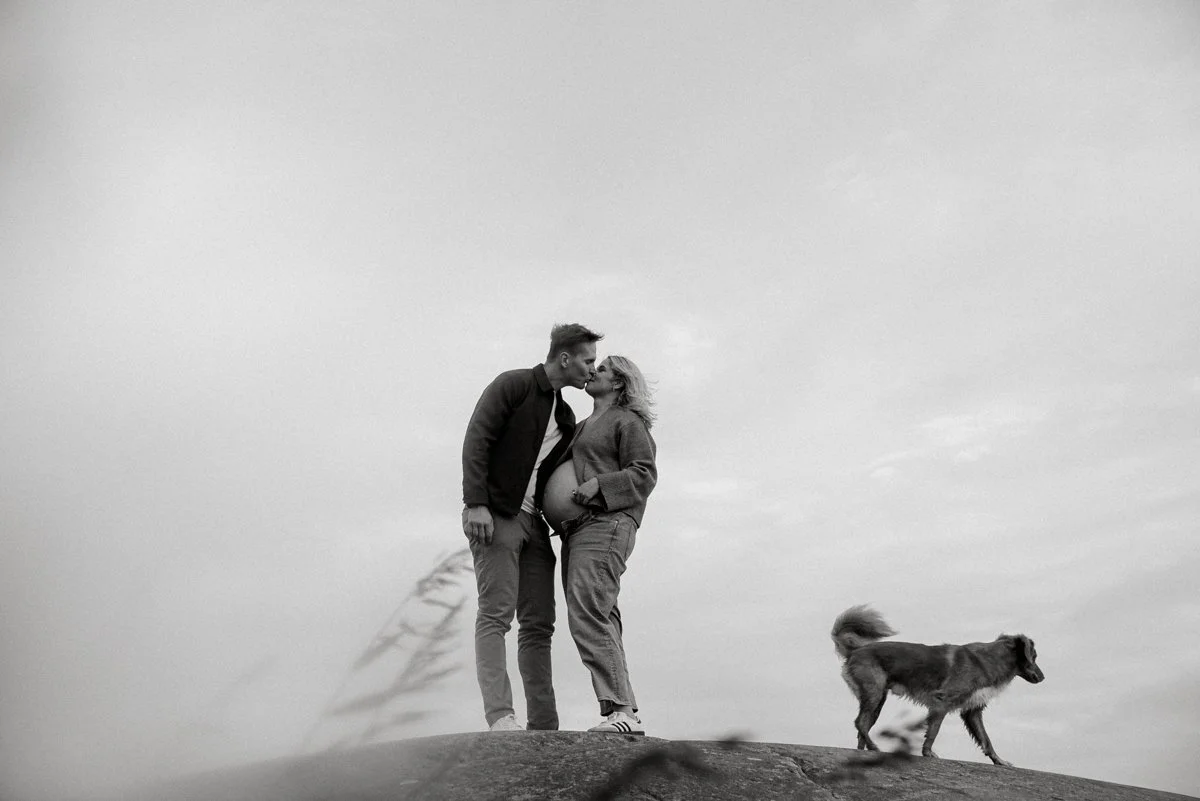 Heidi Väisäsen toteuttama odotusajankuvaus, pariskunta suutelee kalliolla.