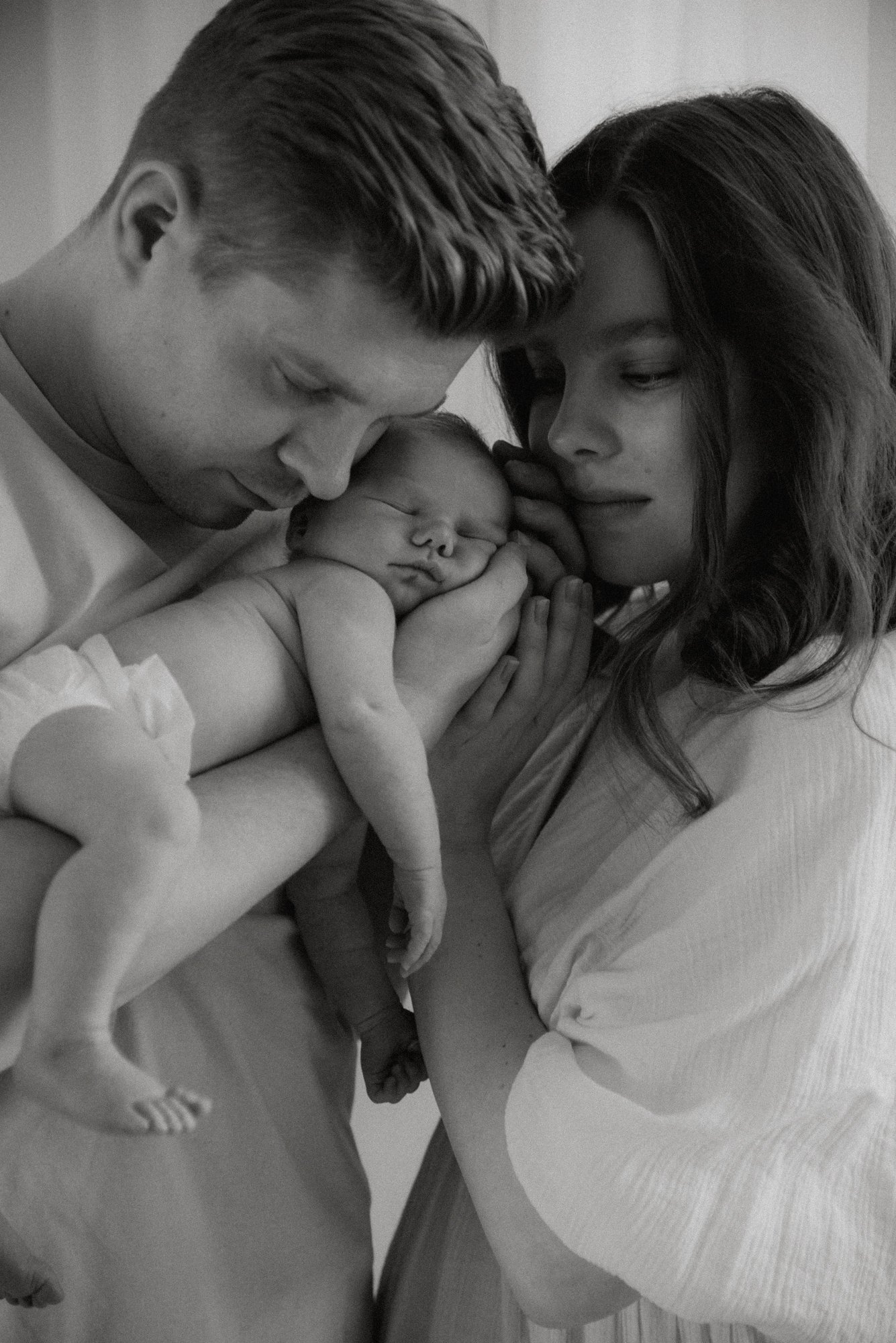 Perhe nojautuneena yhteen rauhallisessa tunnelmassa. Kuvan on ottanut vauvakuvaaja Heidi Väisänen.