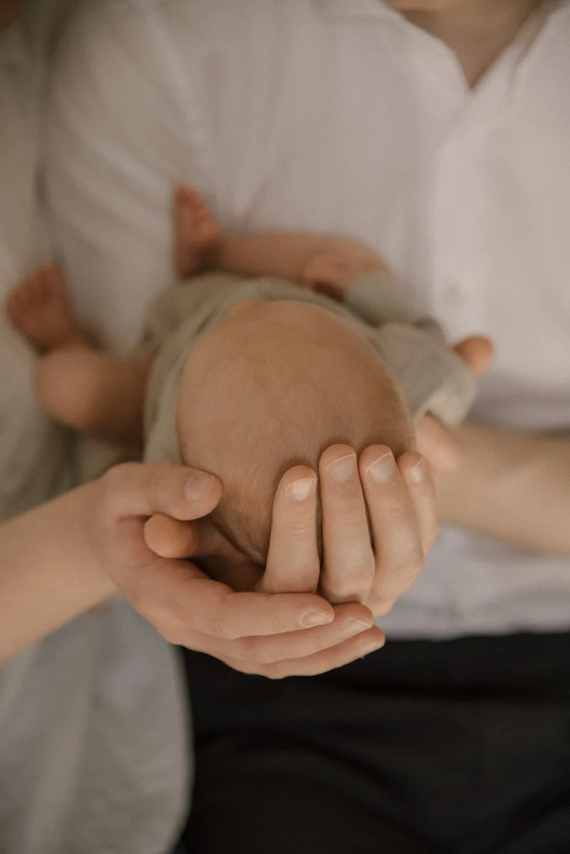 Vastasyntynyt äidin ja isän syleilyssä perhekuvauksessa.