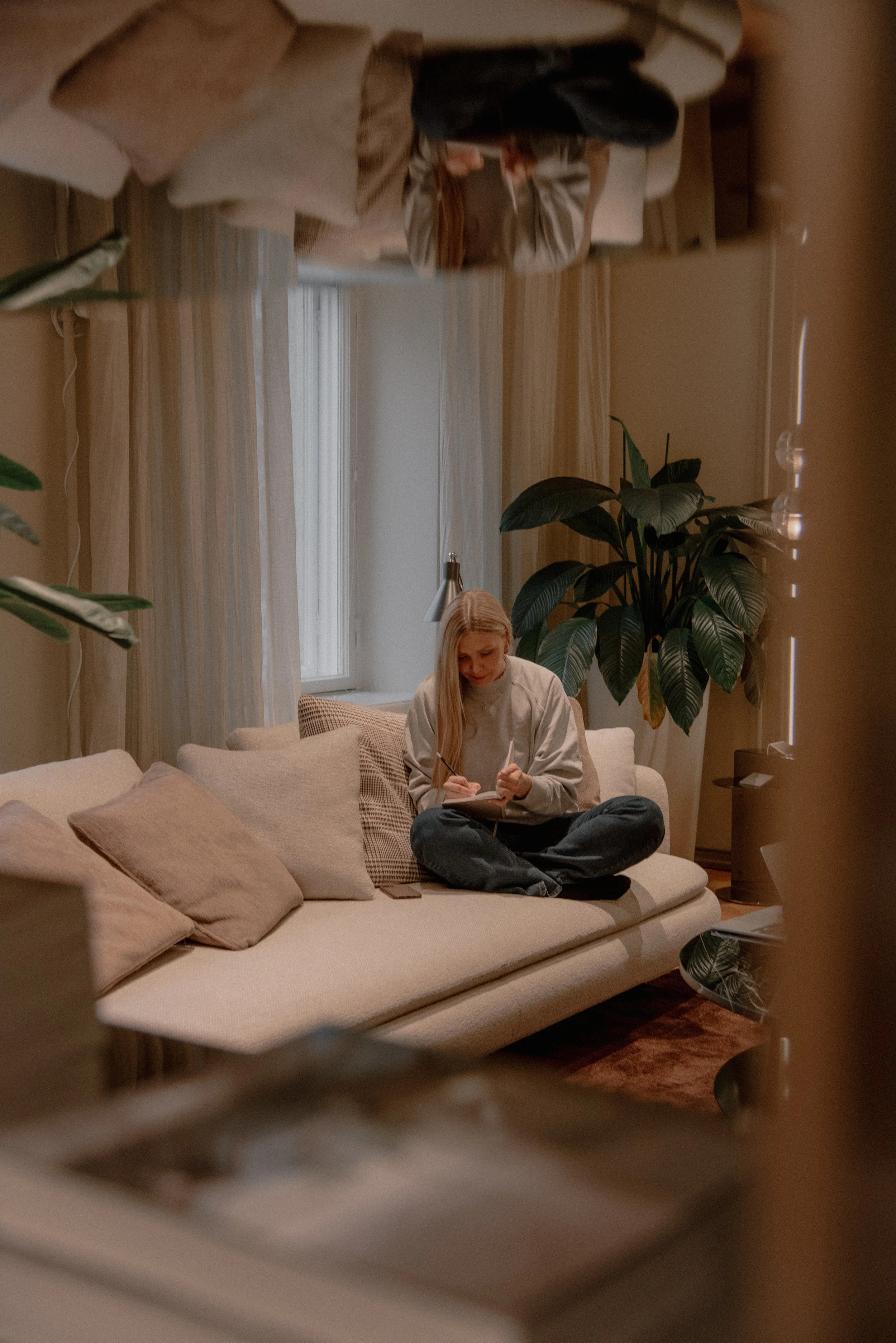 Naisyrittäjä kirjoittaa muistiinpanoja vaalealla sohvalla