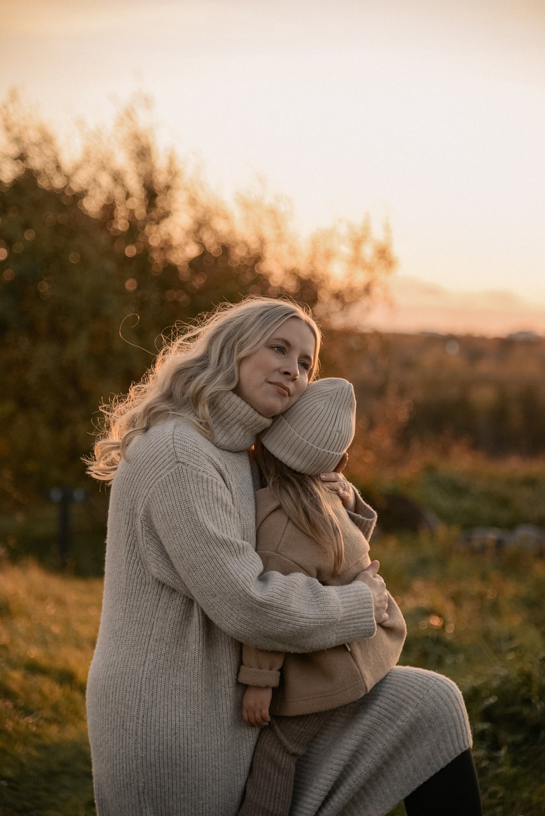 Perhekuvaus Helsinki, äiti halaa lastaan luontomaisemassa ilta-auringossa.