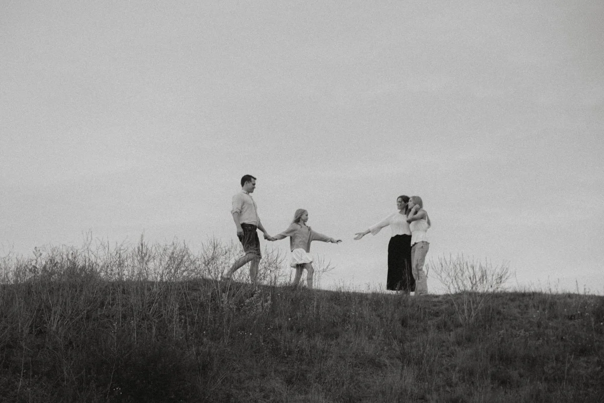 Perhe kävelee maastossa, lapsi ja vanhemmat, mustavalkokuva.