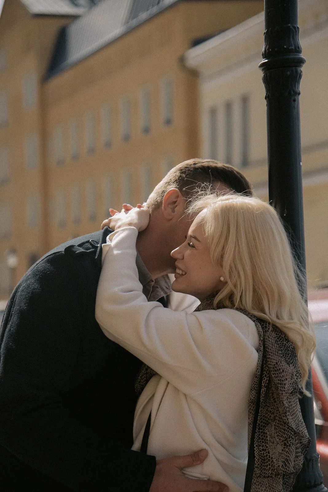 Pariskuntakuva, jossa pari halaa toisiaan kaupunkimaisemassa.