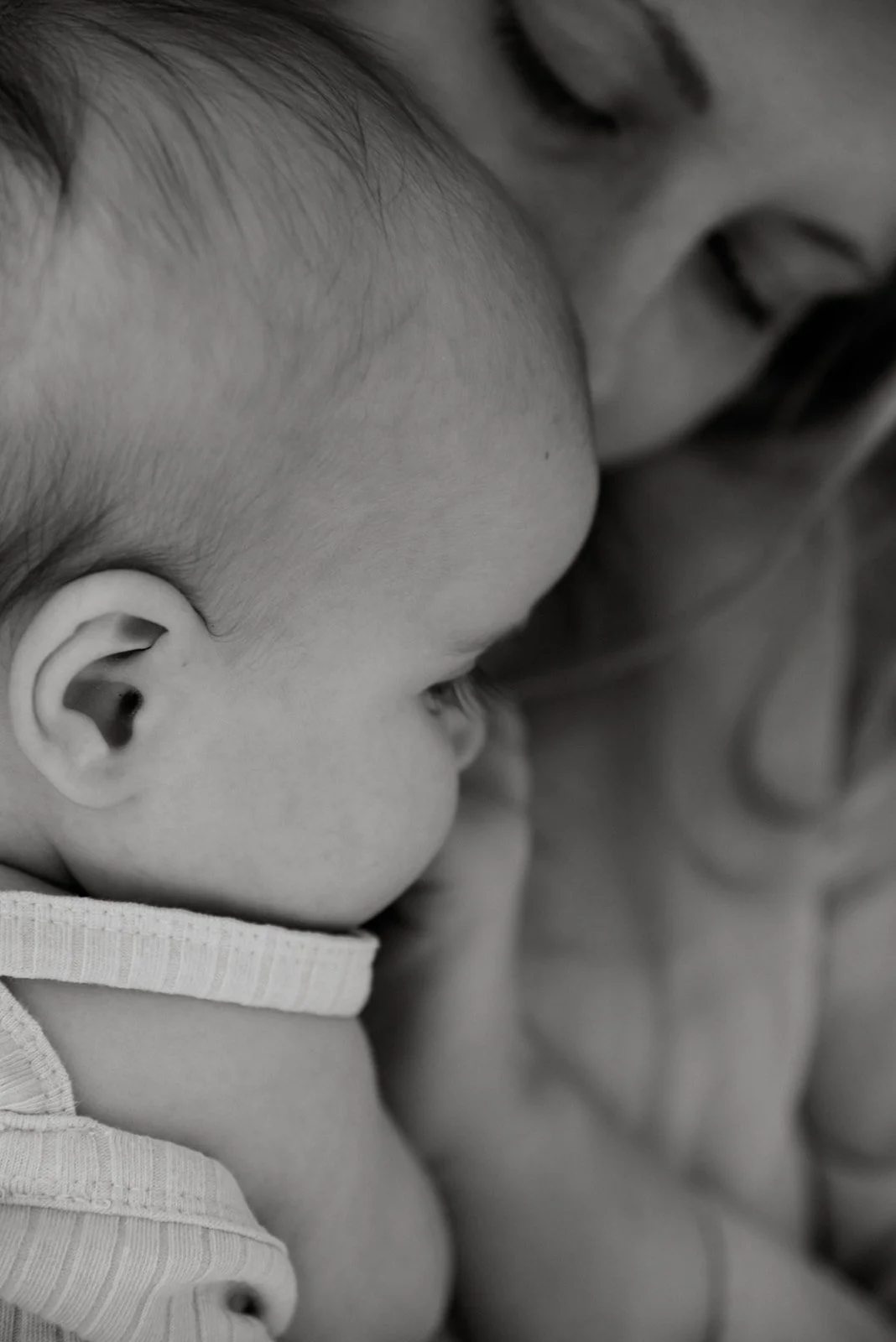 Äidin ja vauvan yhteinen kuva, jossa äiti koskettaa lastaan rauhoittavasti.
