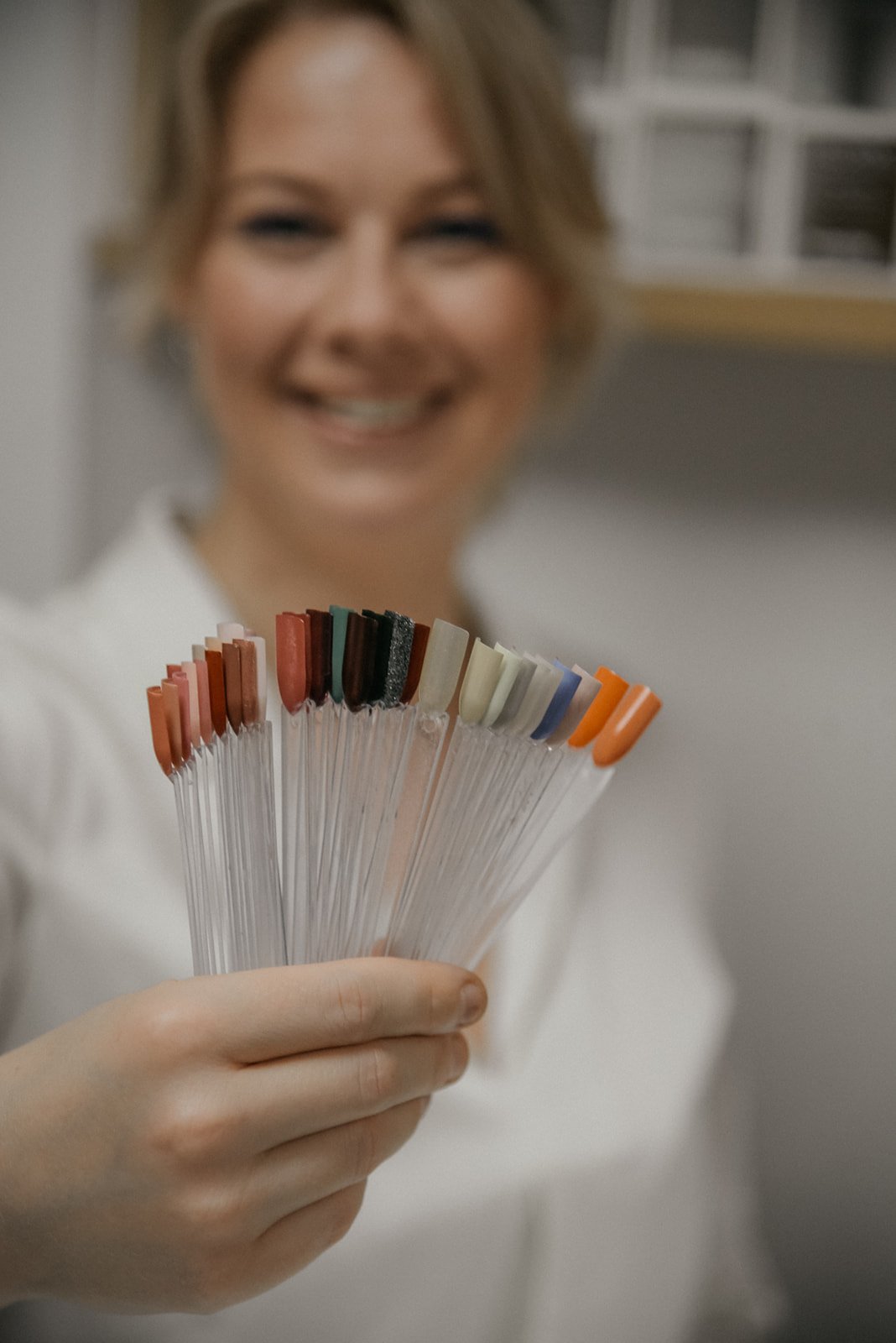 Iloinen työntekijä näyttää kynsiviuhkaa. Kuvannut brändikuvaaja Heidi Väisänen.