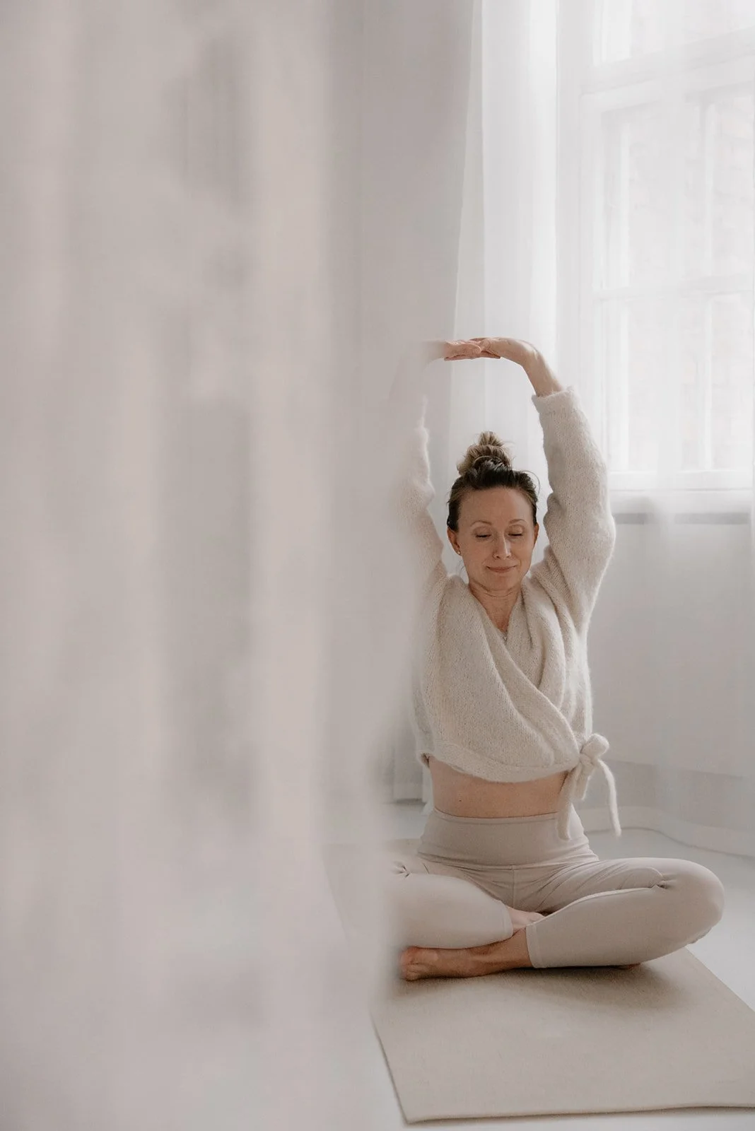 Yrittäjä venyttelee harmonisen kuvausstudion lattialla joogamatolla. Kuvannut yrityskuvaaja Heidi Väisänen.