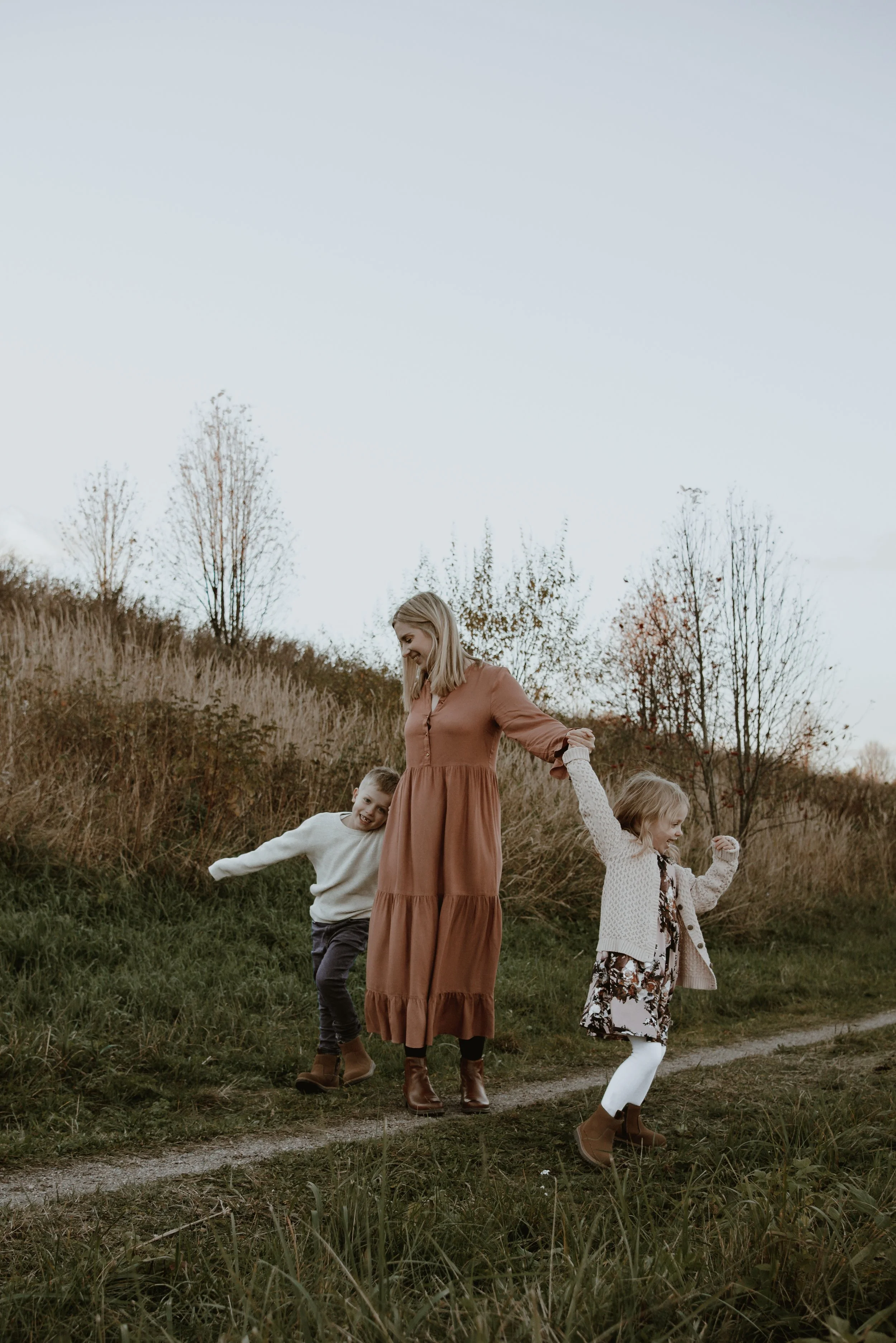 Perhekuvaus Helsinki, äiti ja lapset kävelevät käsi kädessä luonnnossa.