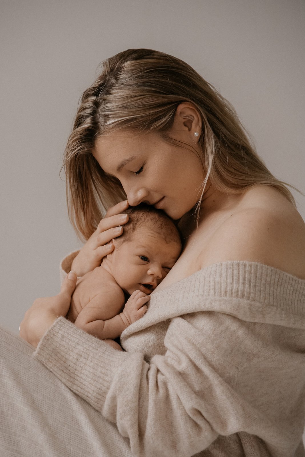 Vanhempi pitää vastasyntynyttä sylissään. Vauvakuvaus valokuvaaja Heidi Väisäsen studiolla Keravan Saviossa.