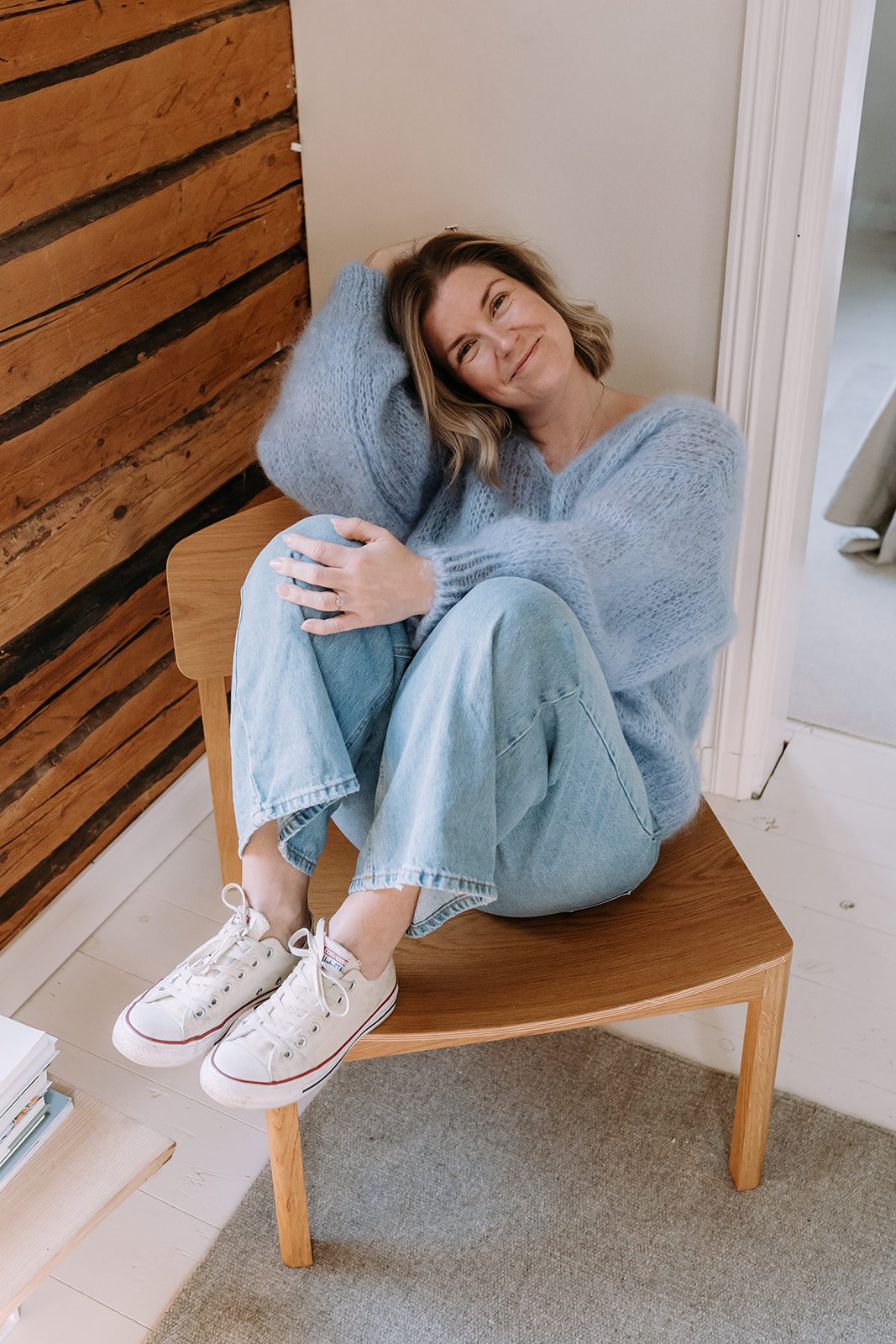 Valokuvaaja Heidi Väisänen istuu tuolilla vaaleansinisessä neuleessa.