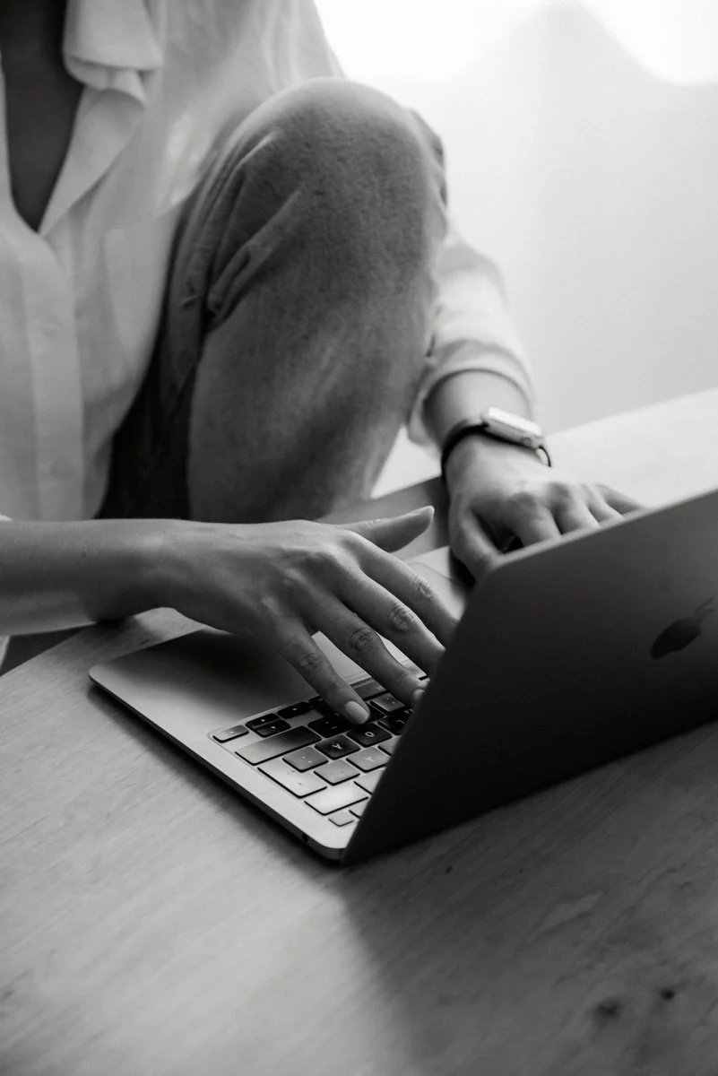 Valokuvaaja Heidi Väisäsen ottama mustavalkoinen yrityskuva, jossa yrittäjä kirjoittaa tietokoneella.