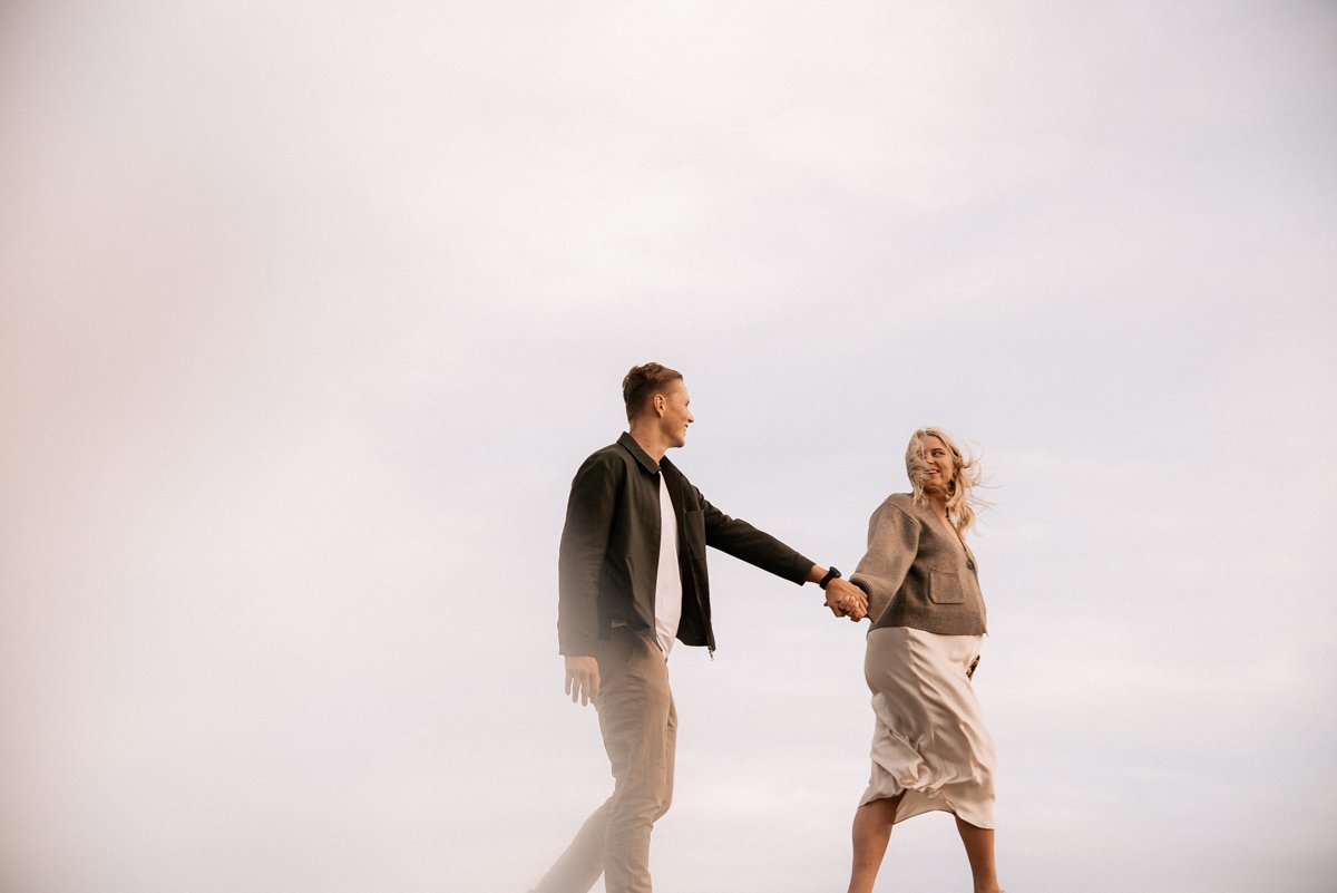 Tulevat vanhemmat kävelevät käsi kädessä ulkona toisiinsa katsoen. Odotusajankuvaus Espoo.