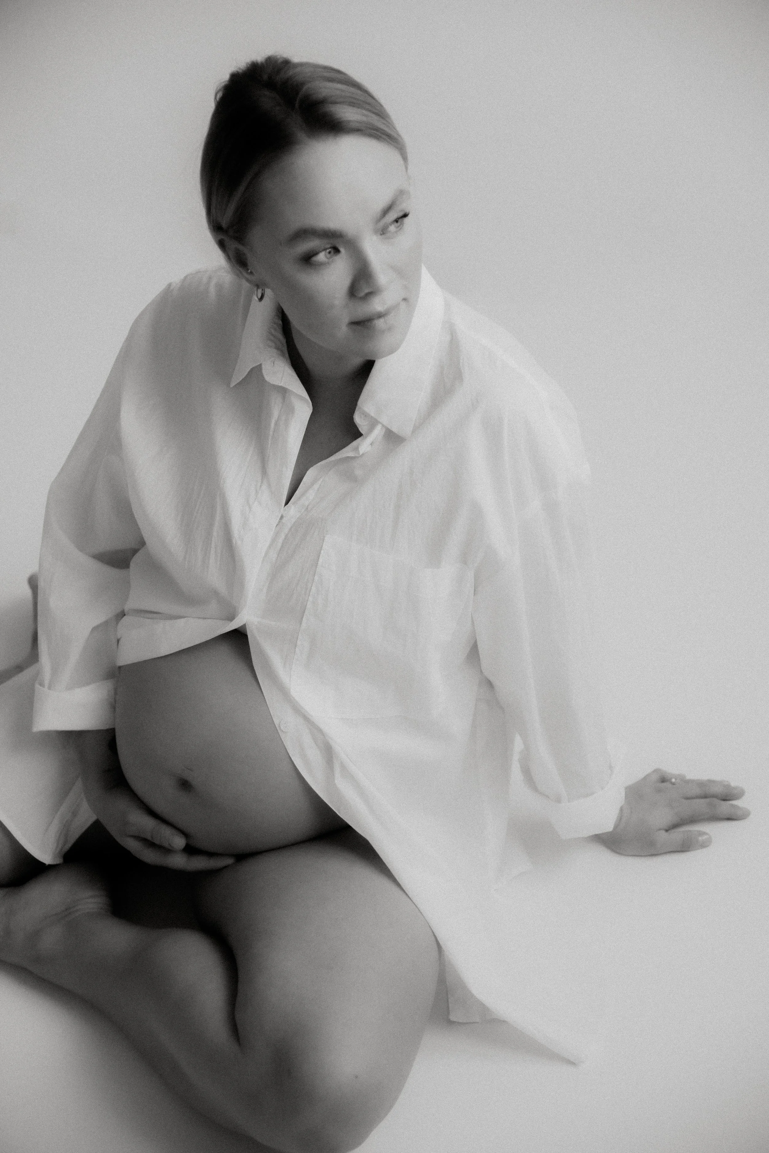 Raskaana oleva äiti istuu studion lattialla. Odotusajankuvaus Heidi Väisäsen studiolla Keravan Saviossa.