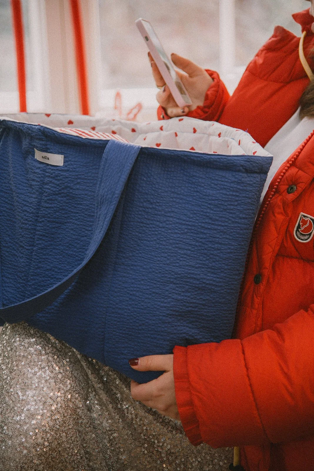 Tuotekuva, jossa naisyrittäjän sylissä iso sininen Edlan laukku.