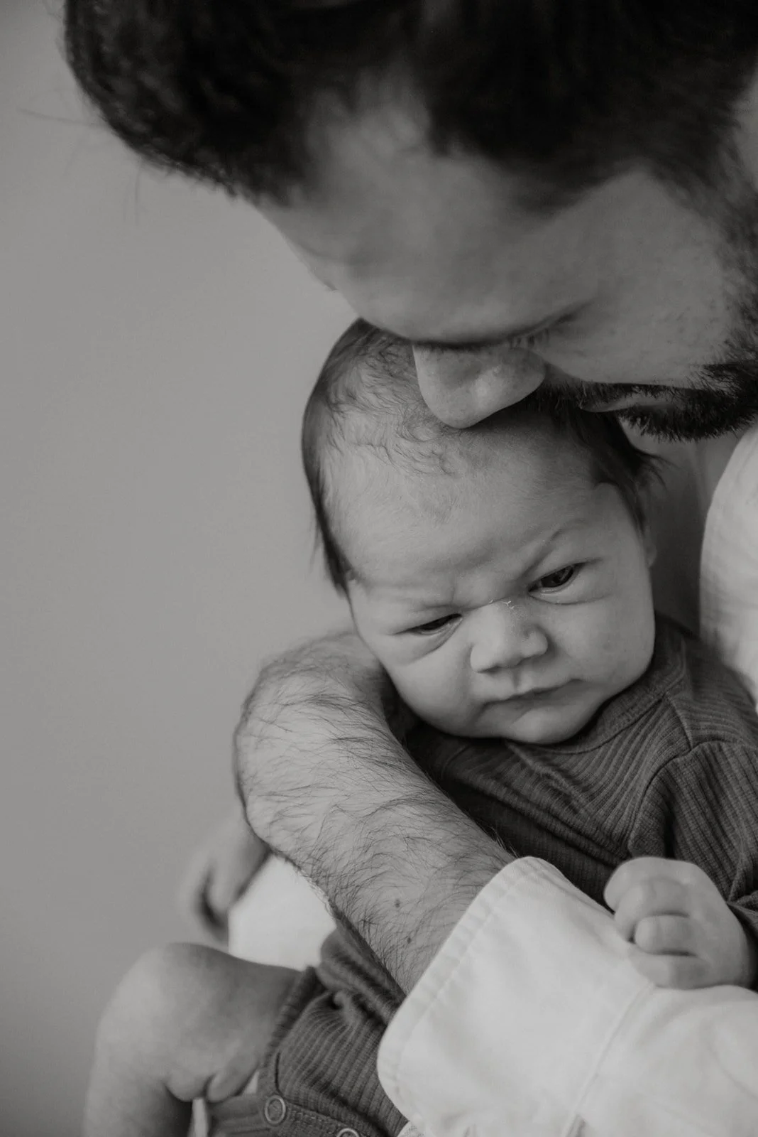 Mustavalkoisessa lähikuvassa vauvan ensi hetkiä isän kanssa. Vauvakuvaus Uusimaa.