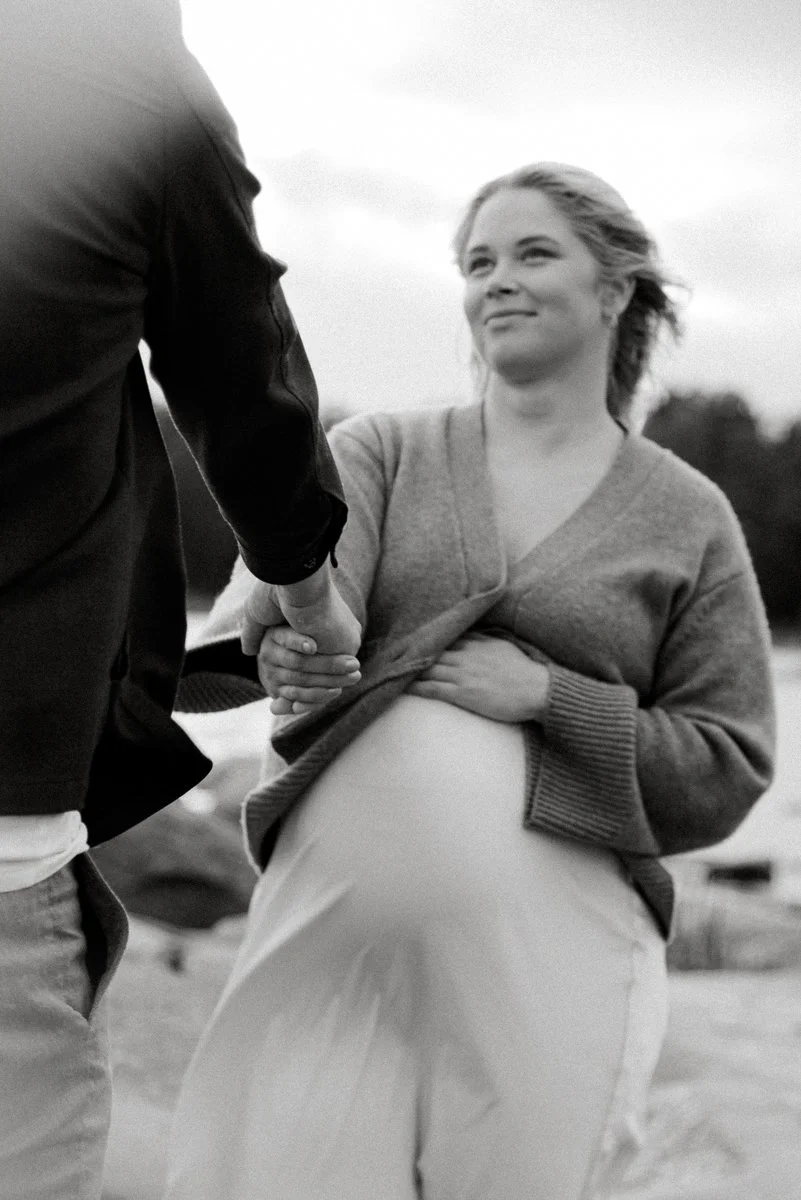 Mustavalkoinen raskauskuva, jossa odottava äiti pitelee kättään vatsan päällä.