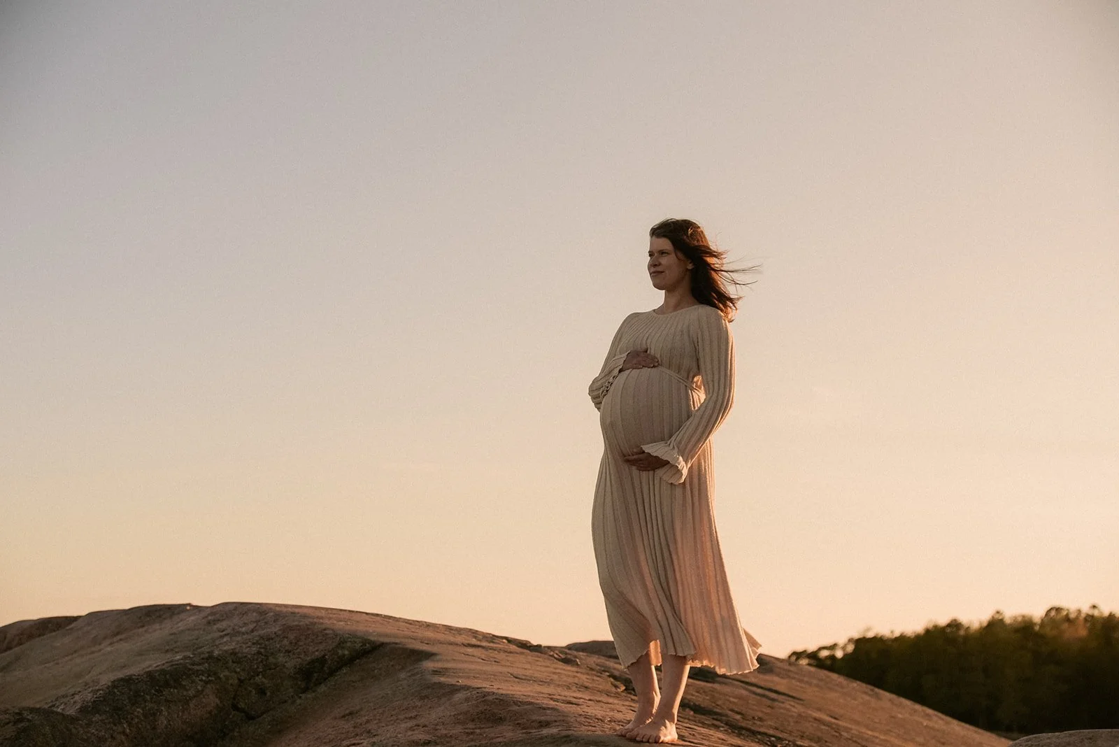 Harmoninen kuva, jossa odottava äiti seisoo kalliolla ja katsoo kaukaisuuteen. Odotusajankuvauksen on toteuttanut valokuvaaja Heidi Väisänen.