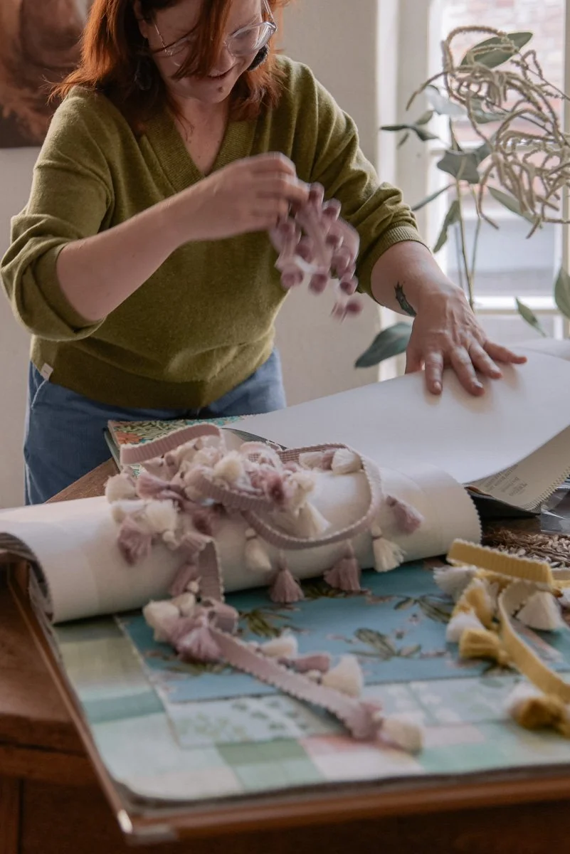 Verhoomoyrittäjä Virve työssään, pöydällä verhoomon tarvikkeita. Kuvannut yrityskuvaaja Heidi Väisänen.