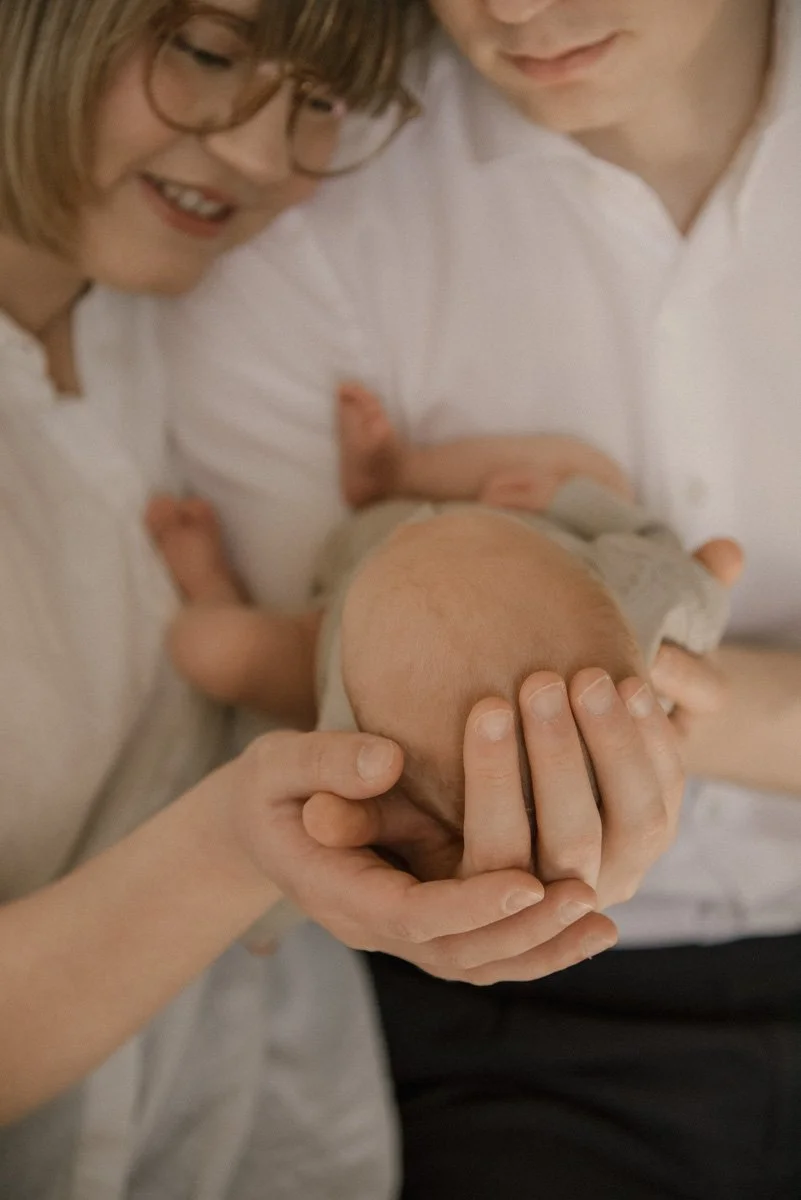 Vastasyntynyt hellässä vanhempien syleilyssä. Kuvan on ottanut vauvakuvaaja Heidi Väisänen.