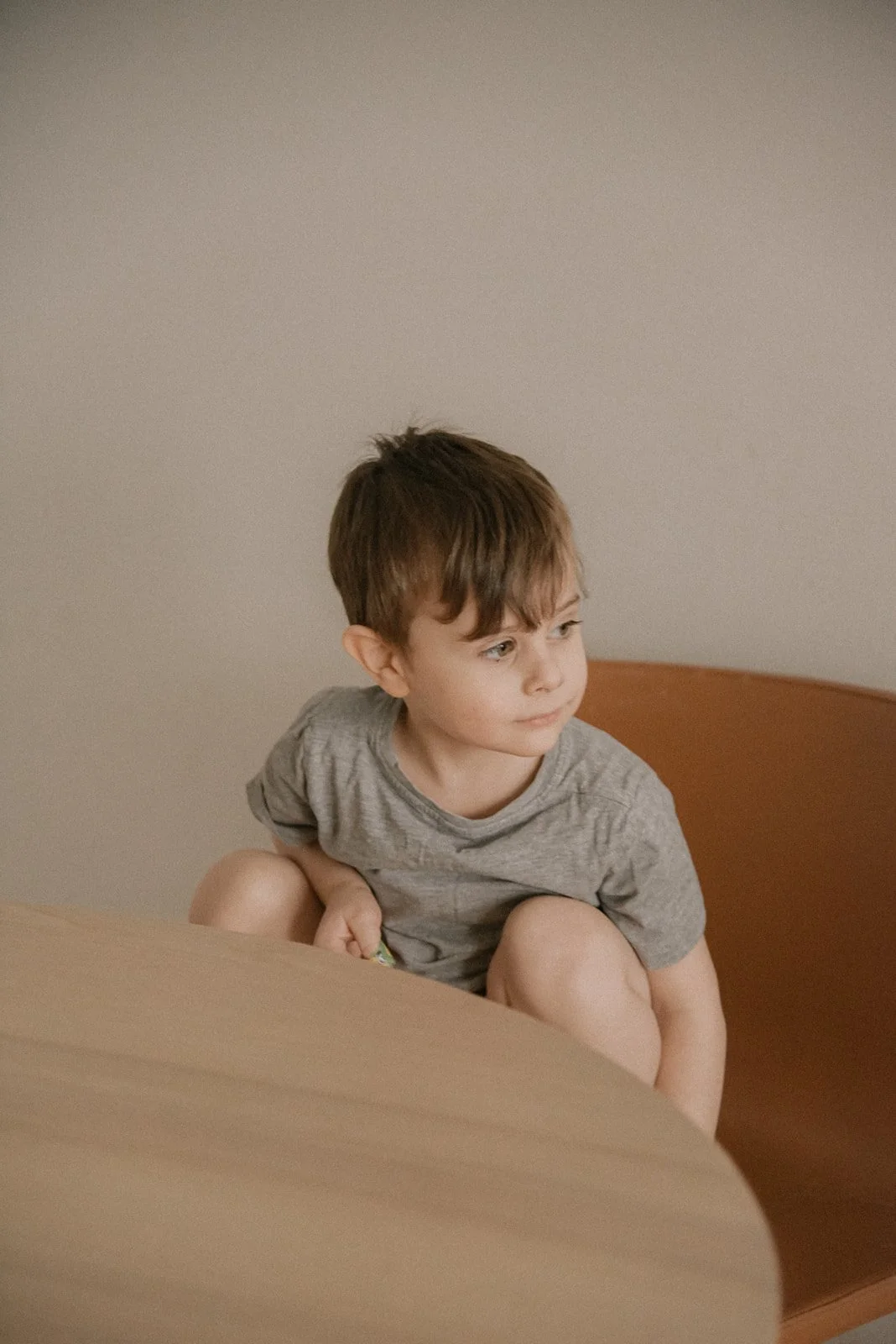 Mietteliäs lapsi istuu pöydän ääressä. Lapsikuvaus Helsinki.