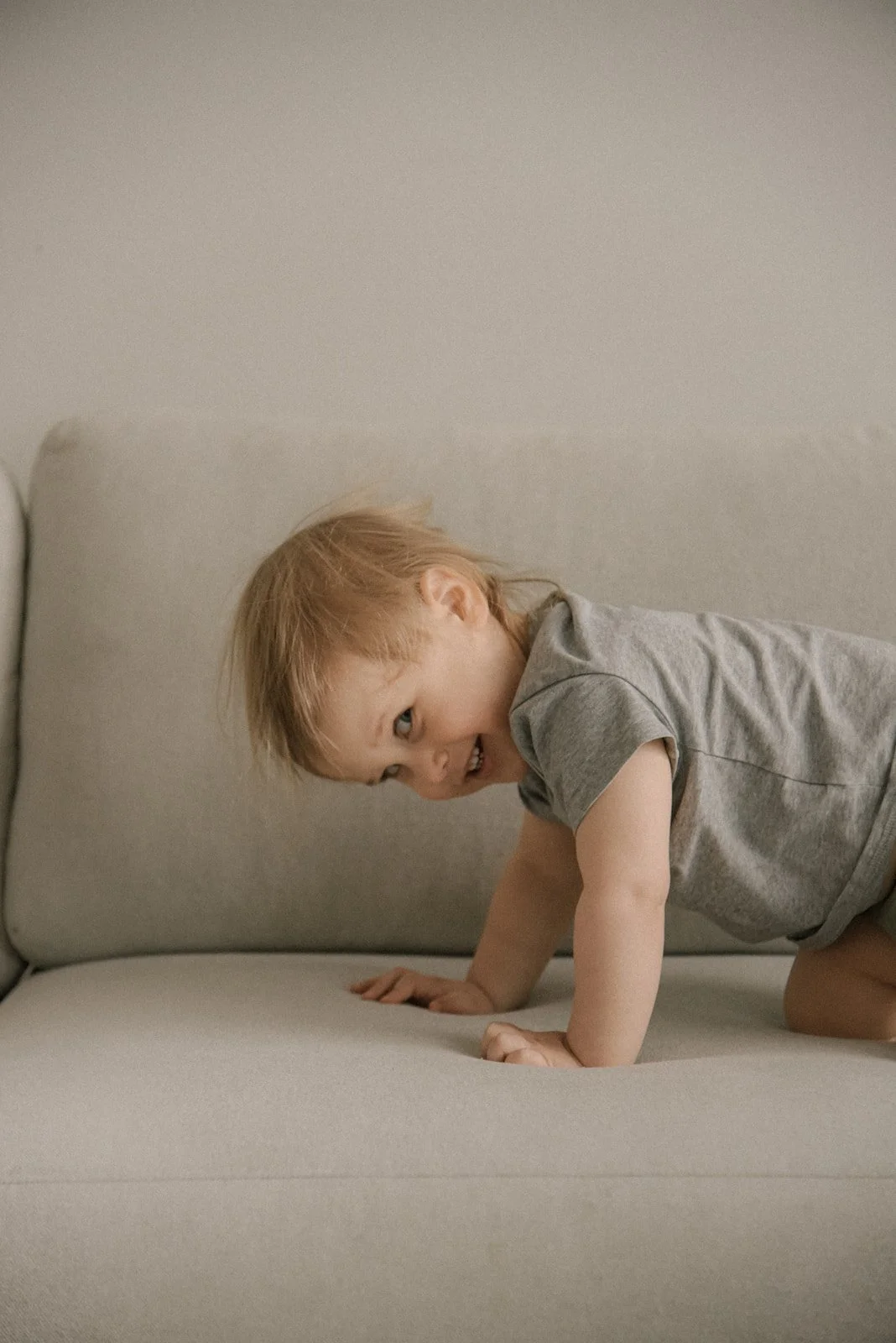 Lapsi leikkii iloisesti sohvalla. Lapsikuvaus Helsinki.