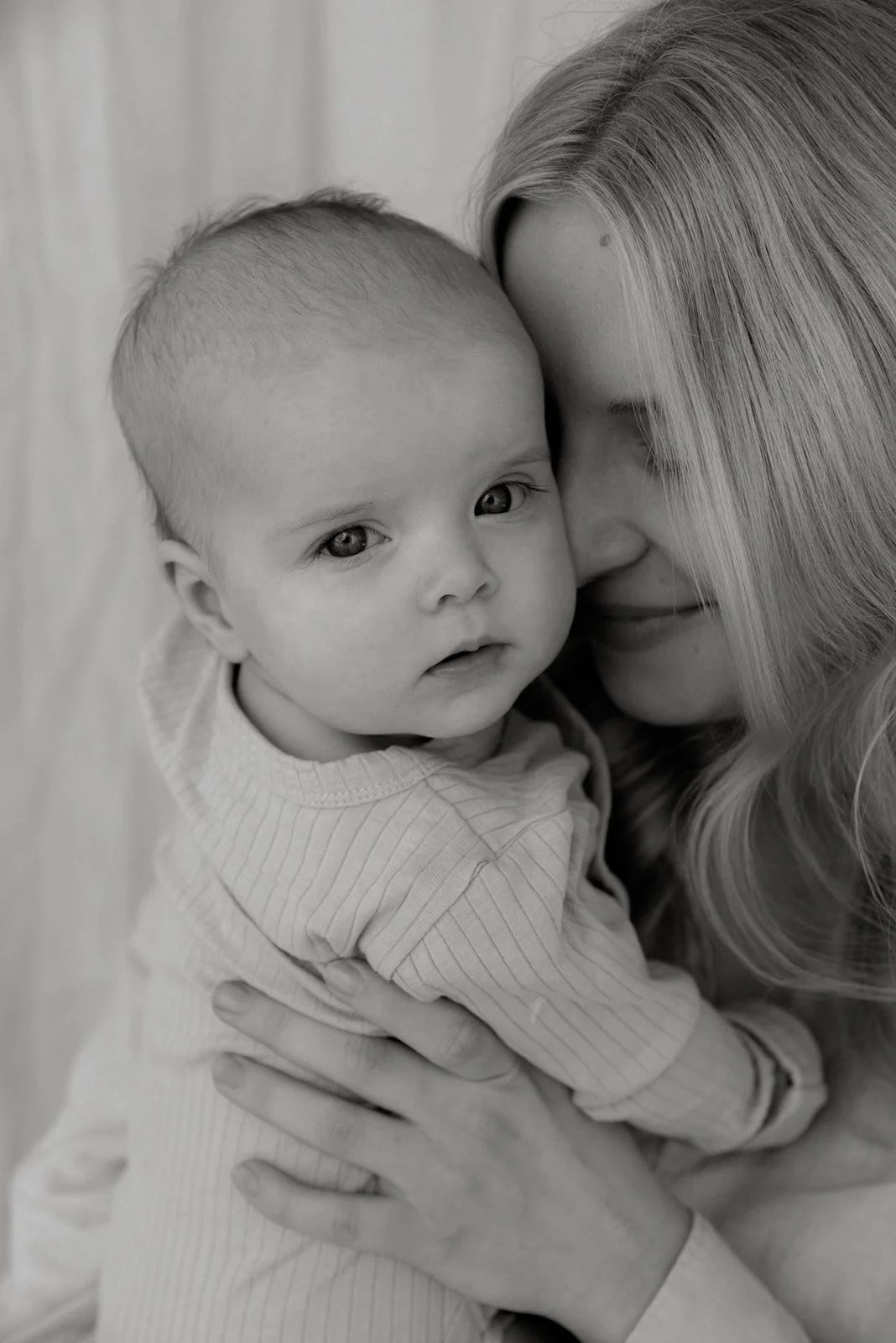 Vauva katsoo mustavalkoisessa kuvassa suoraan kameraan. Äiti- ja lapsikuvaus Heidi Väisäsen studiolla.