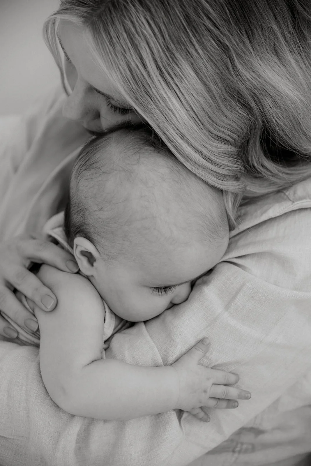 Äidin lämmin syli mustavalkokuvassa. Äiti ja vauva kuvattuna studiolla.