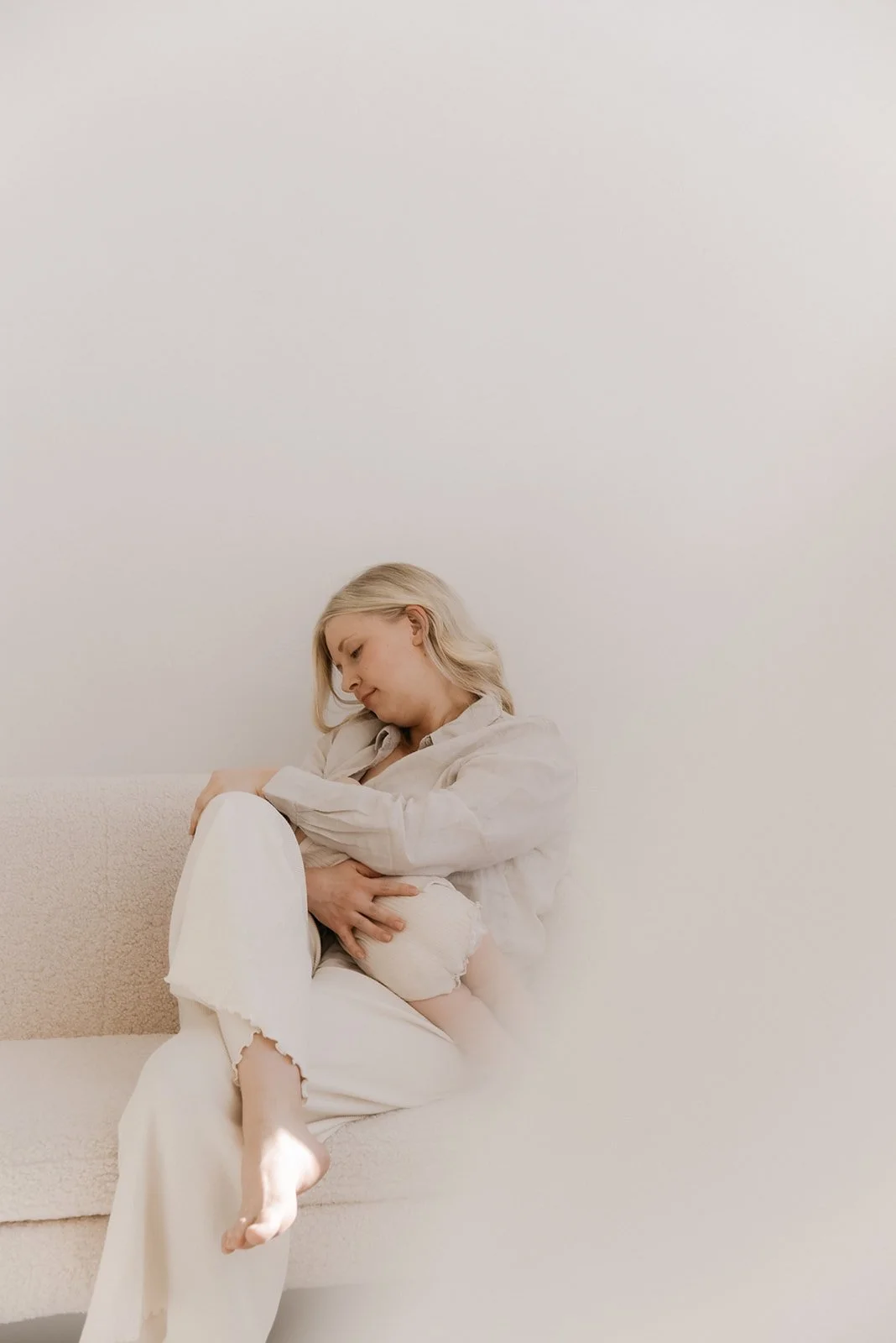 Vaalea ja harmoninen valokuva, jossa vauva on äidin sylissä. Kuvattu Heidi Väisäsen studiolla luonnonvalossa.