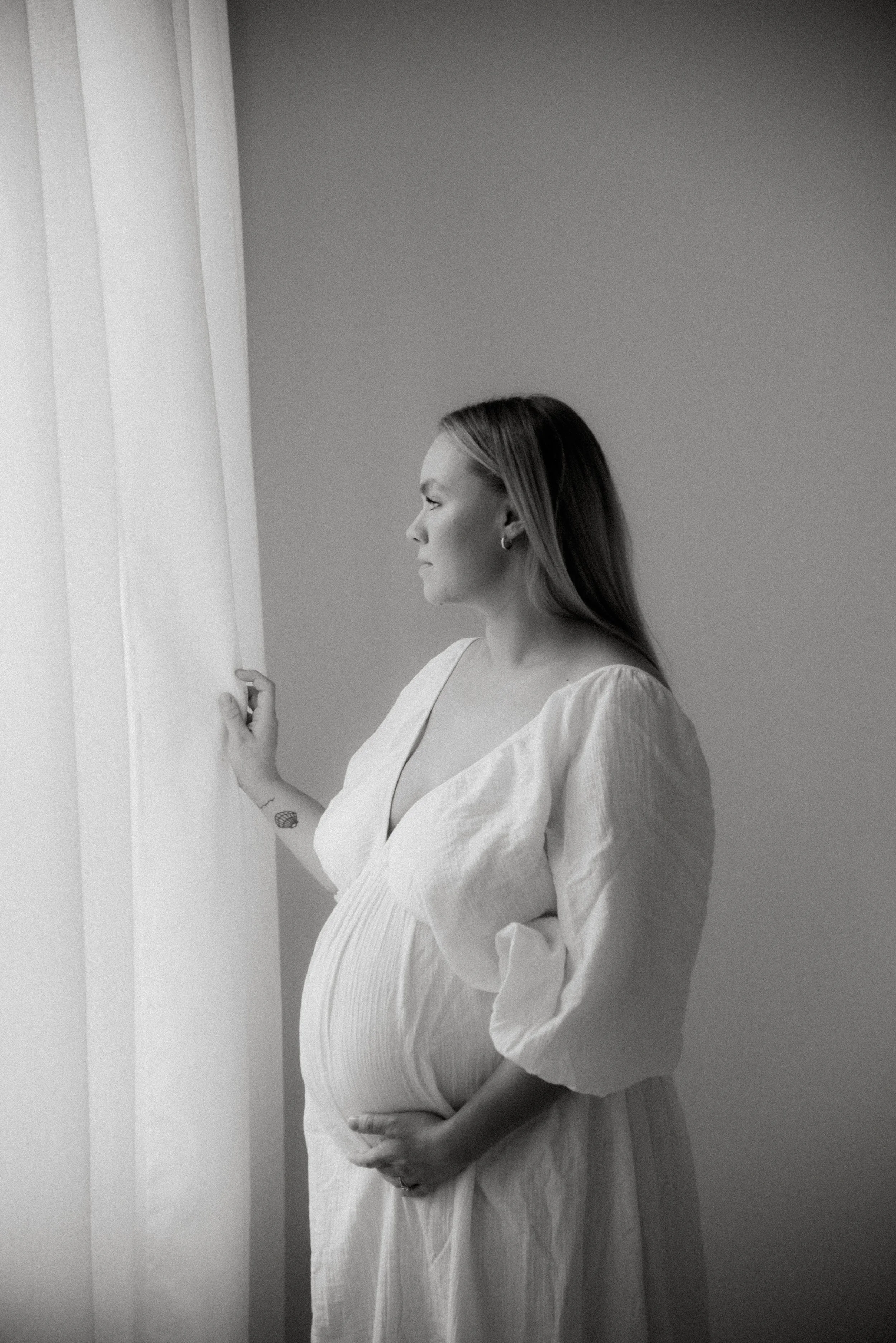 Odottava äiti yllään vaalea mekko. Odotusajankuvaus Heidi Väisäsen studiolla Keravan Saviossa.