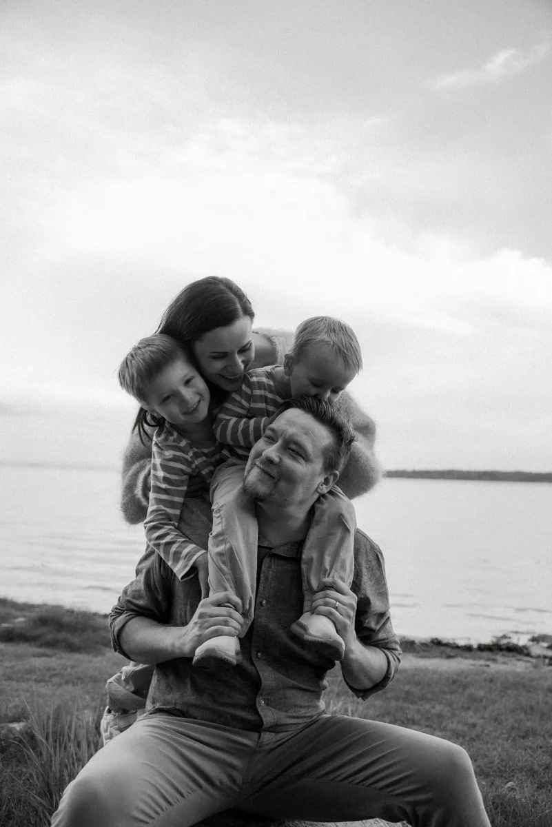Mustavalkoinen perhekuva, äiti, isä ja kaksi lasta rannalla.