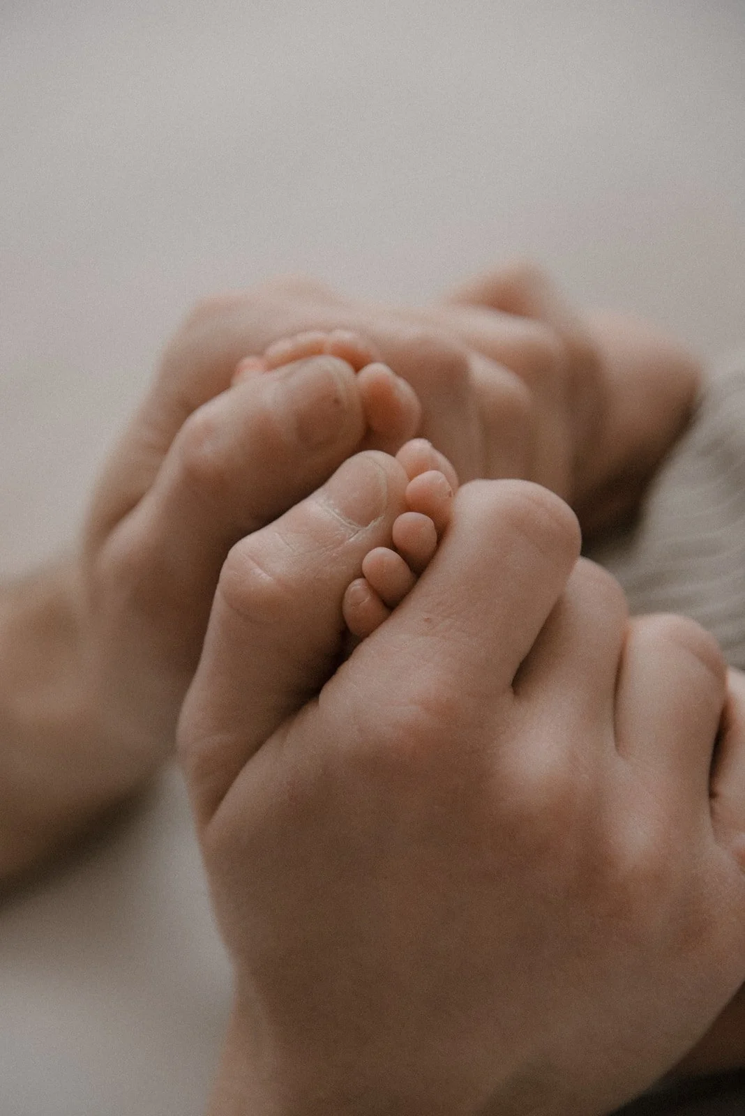 Vauvavuoden kuvaus, pienet varpaat isän käsien välissä.