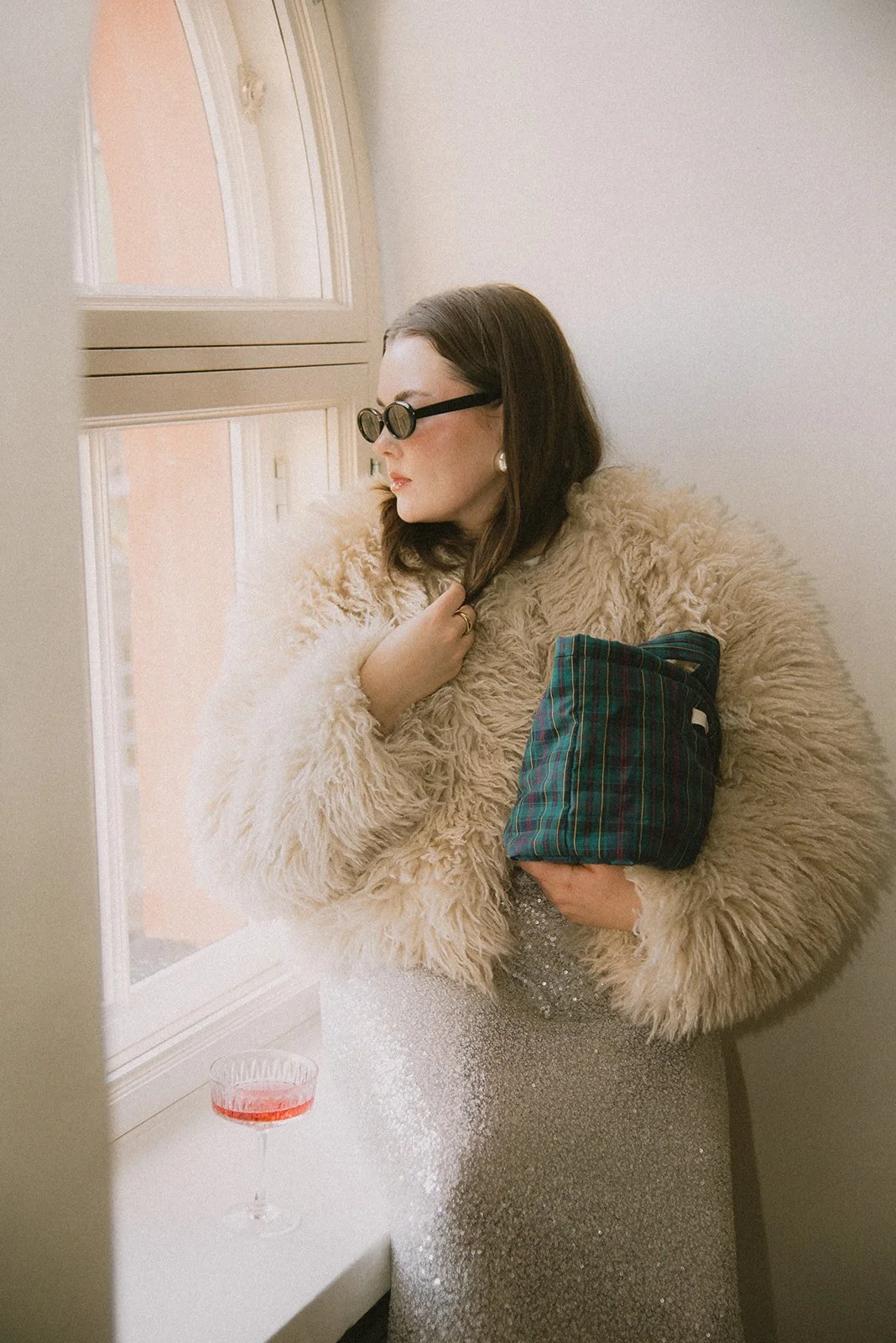 Edlan naisyrittäjä katsoo ikkunasta ulos brändin laukku kainalossa.