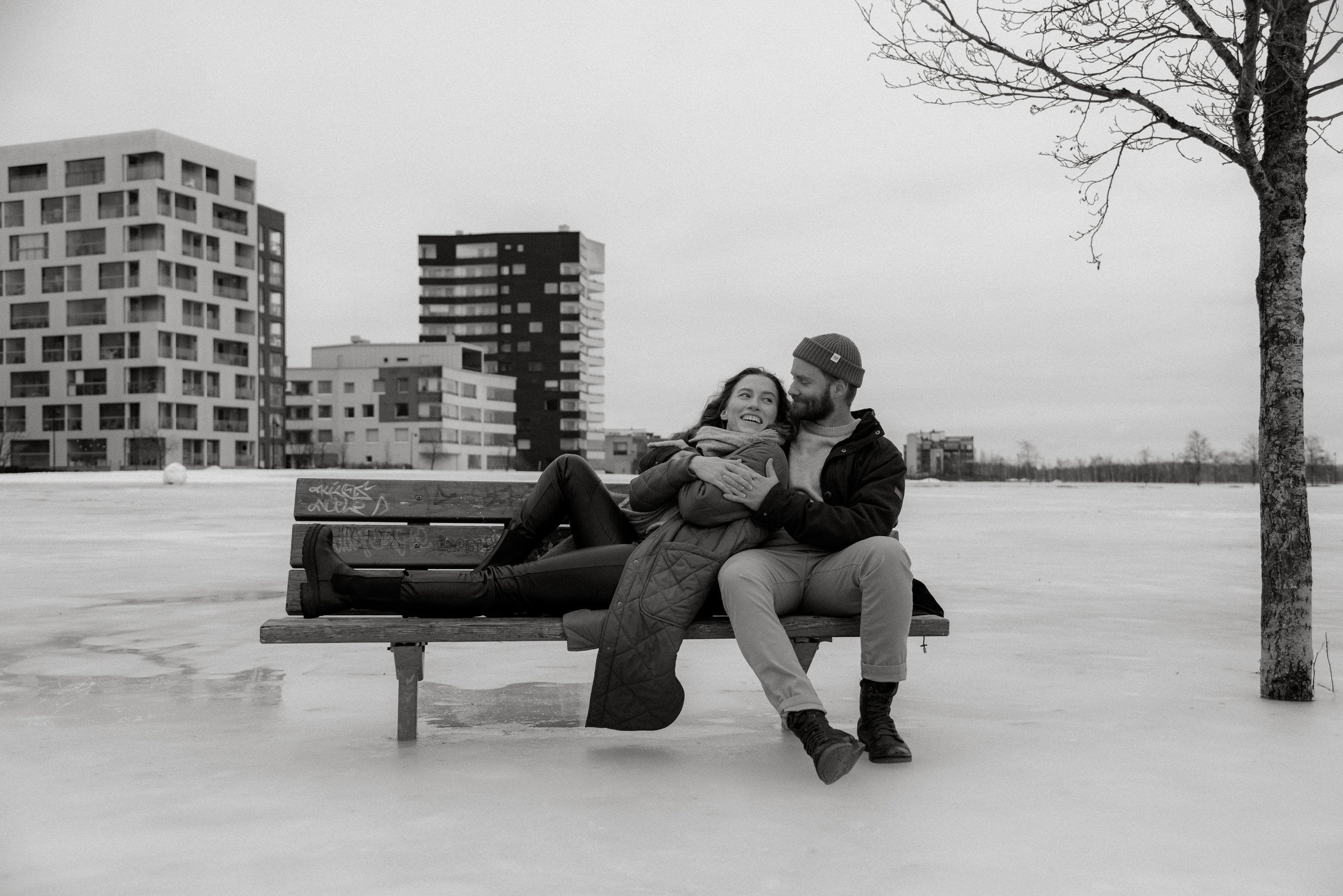 Penkillä istuva halaava pariskunta. Pariskuntakuvaus Espoo.