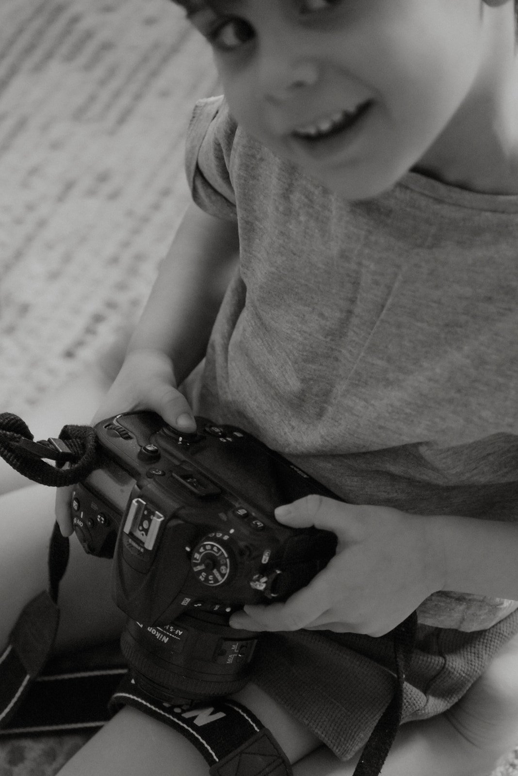 Lapsi katsoo kameraan ja pitelee kameraa käsissään. Lapsikuvaus Helsinki.