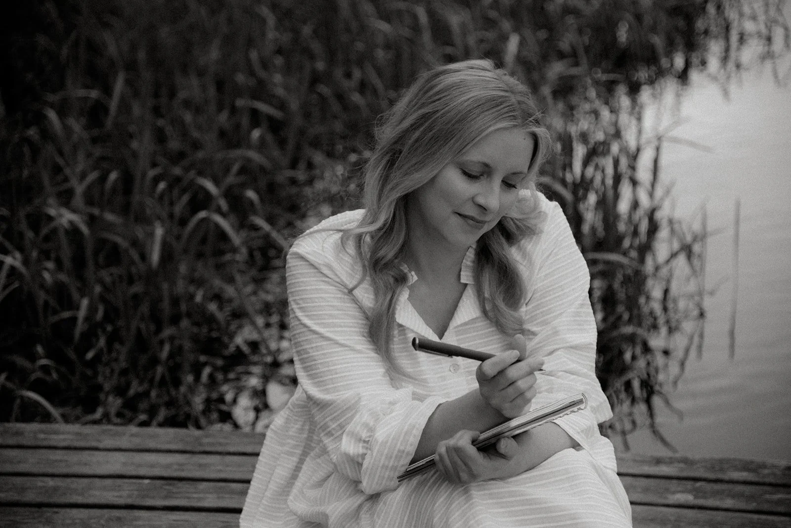 Brändikuvaus luontomaisemassa veden äärellä. Yrittäjä kirjoittaa muistikirjaan.