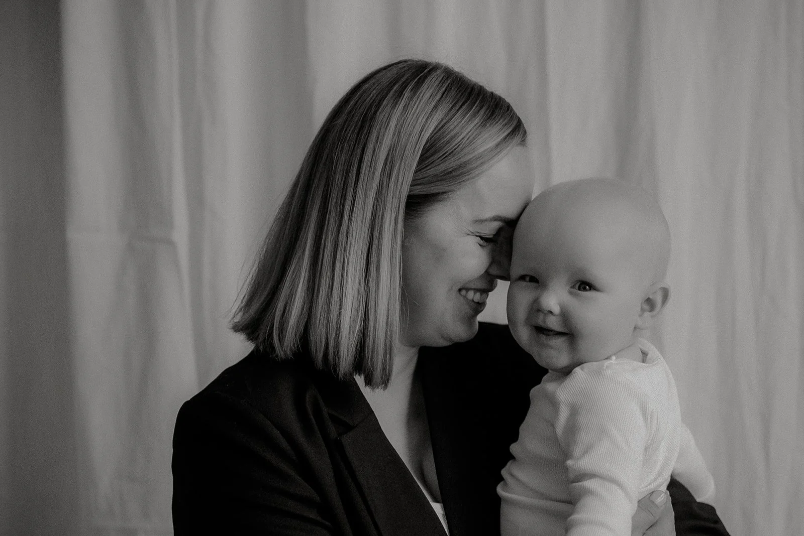 Äiti-lapsikuva, jossa iloinen äiti vauva sylissään. 