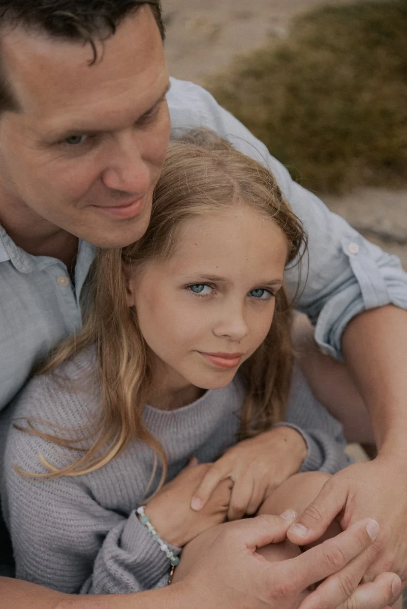 Isä halaa tytärtään sylissään. Perhekuvaus Espoo.