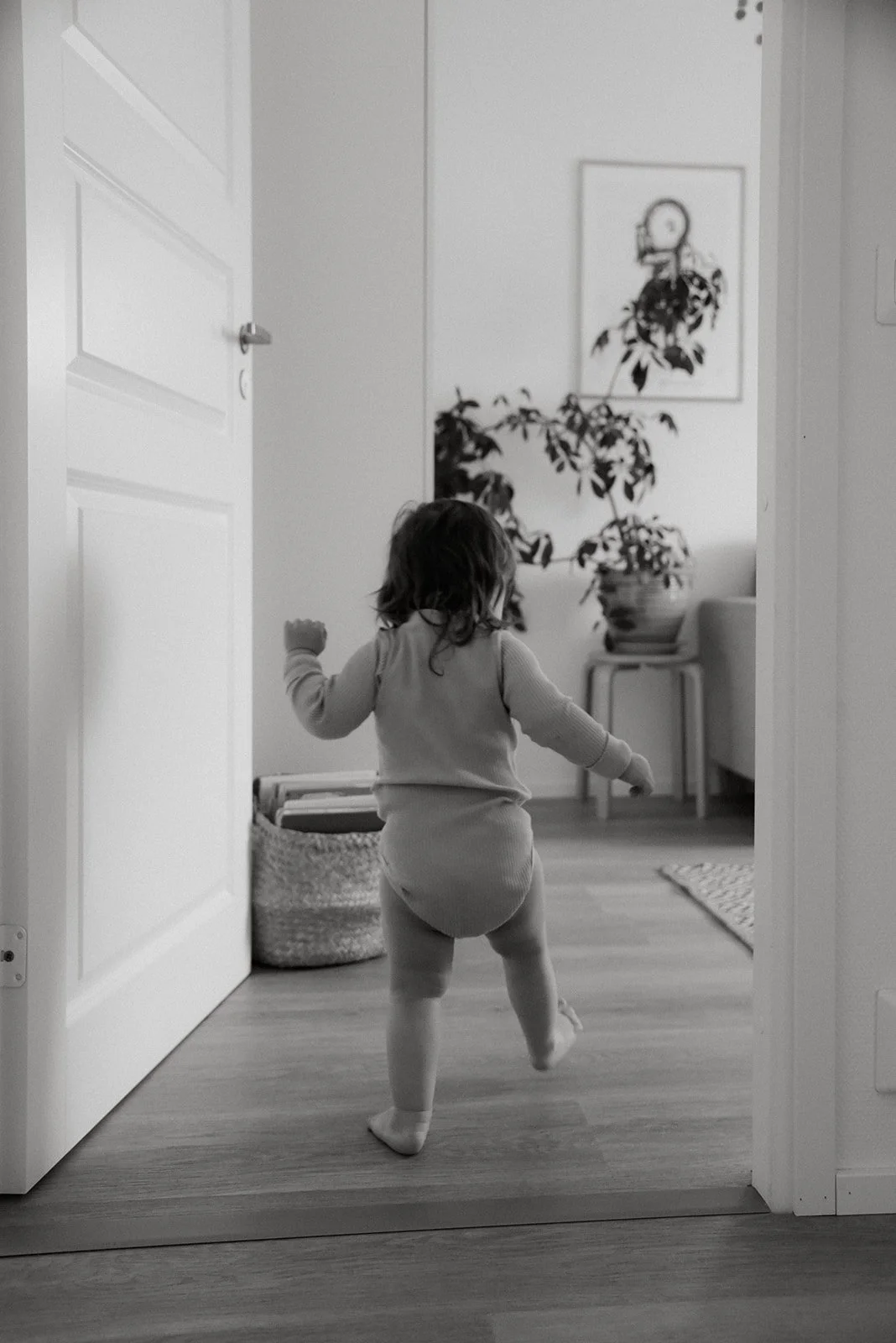 Mustavalkoisessa kuvassa lapsi kävelee kotonaan. Lapsikuvaus kotona, kuvannut valokuvaaja Heidi Väisänen.