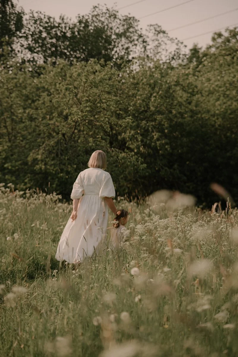 Perhekuvaus miljöössä, äiti ja lapsi kävelemässä niityllä. Kuvannut valokuvaaja Heidi Väisänen.