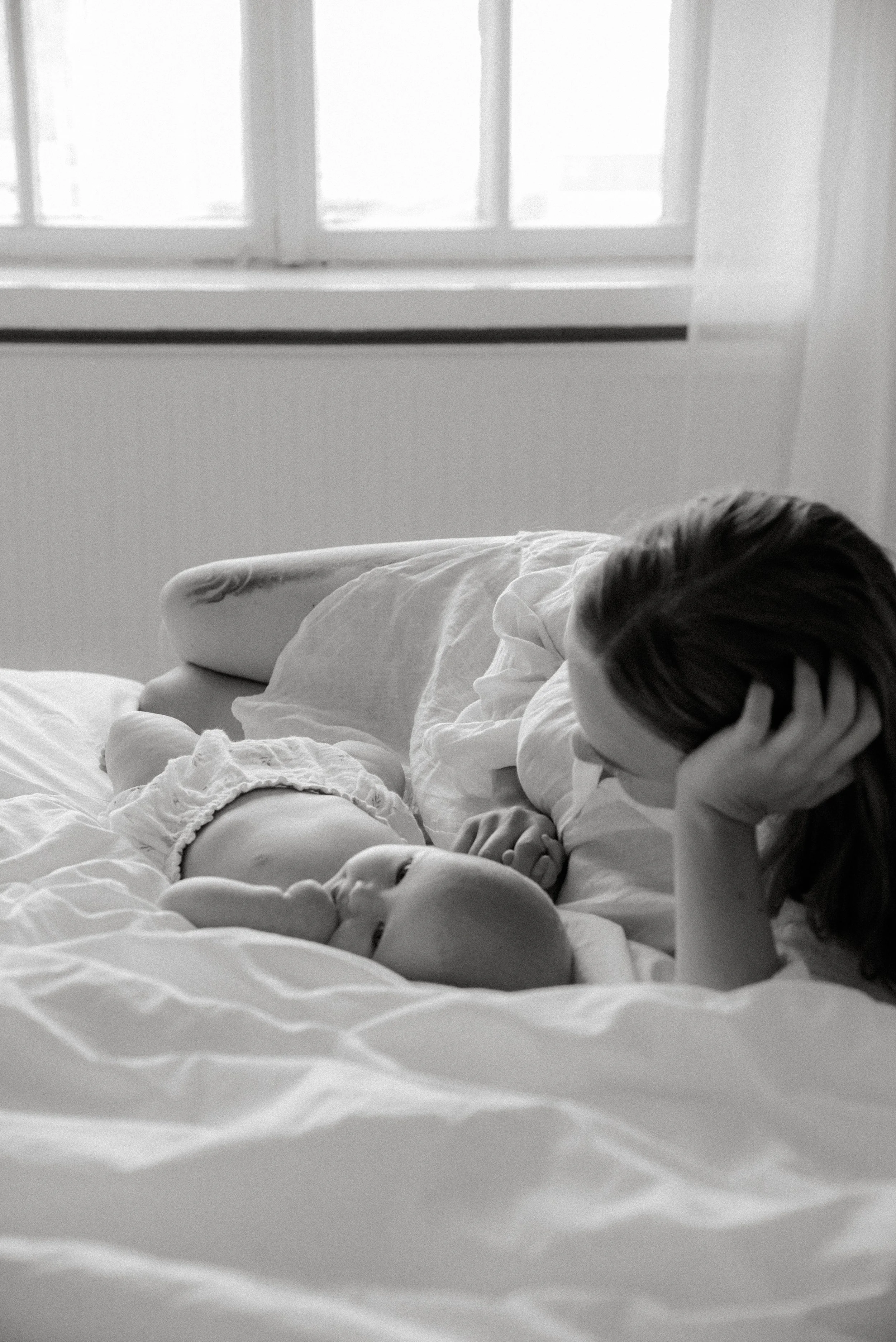 Äiti ja vauva makoilevat rennosti studion sängyllä.