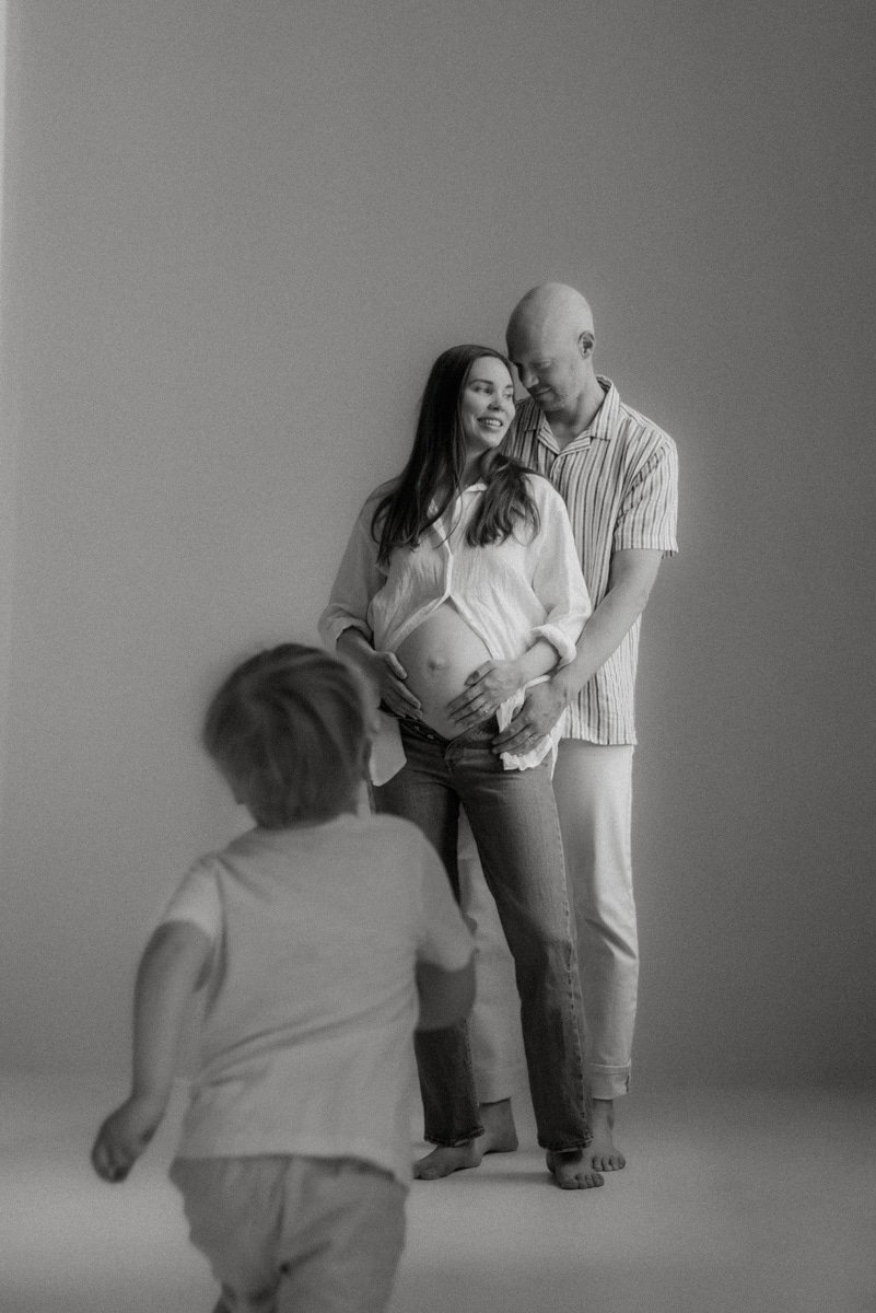 Studiolla kuvattu perhe, jonka äiti odottaa lasta.