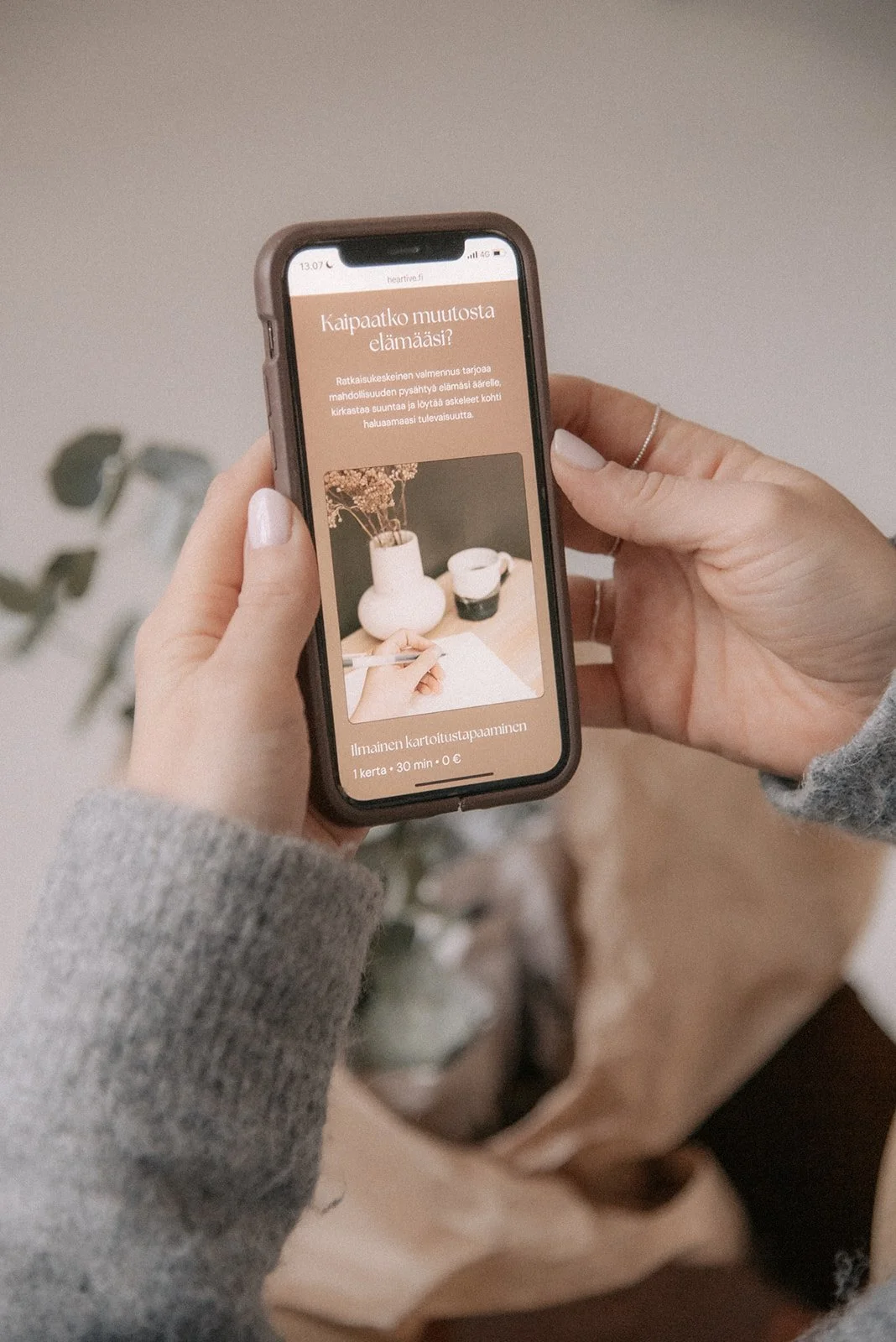 Heartiven yrityskuvaus, yrittäjä Terhi Lahti pitelee käsissään puhelinta jossa näkyy hänen nettisivunsa.