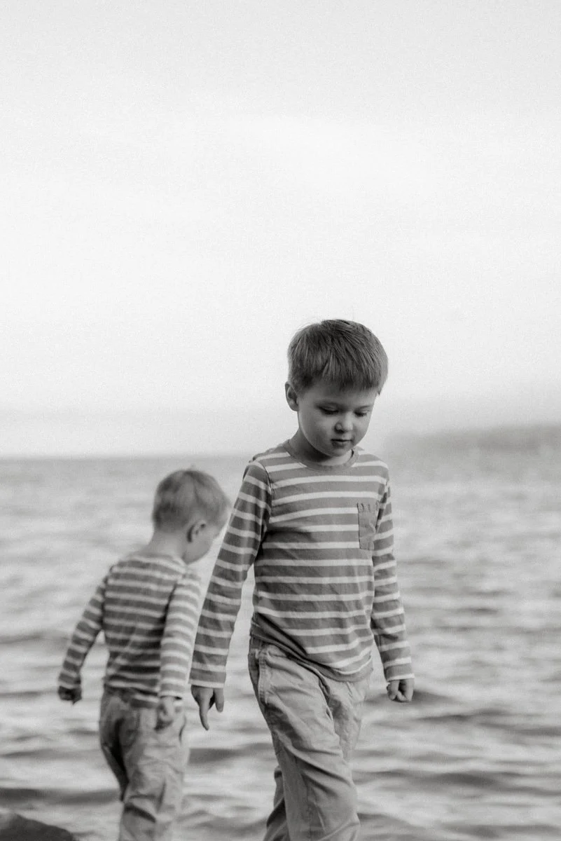 Perhekuvaus miljöössä, kaksi lasta kävelevät veden äärellä. Kuvaaja Heidi Väisänen.